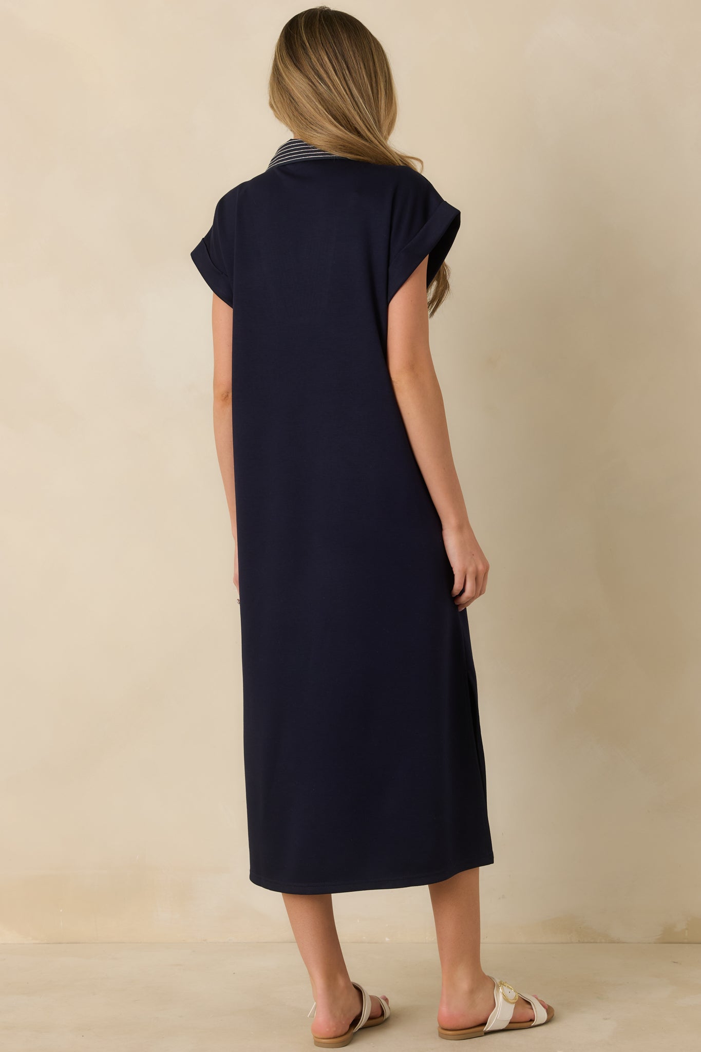 Navy knit midi dress showing the straight silhouette from the rear with a smooth knit finish and midi-length hem.