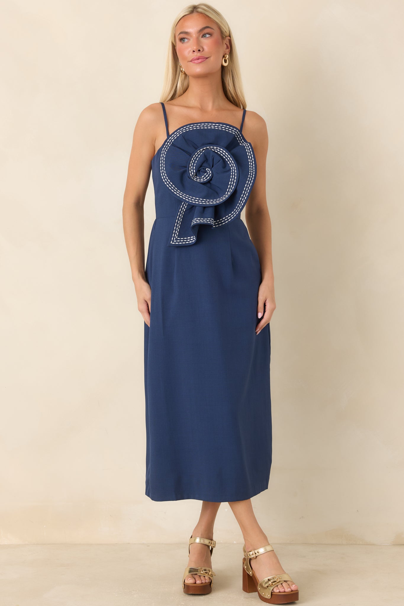 Navy dress showcasing a dimensional rosette detail, full skirt, and elegant fitted silhouette.
