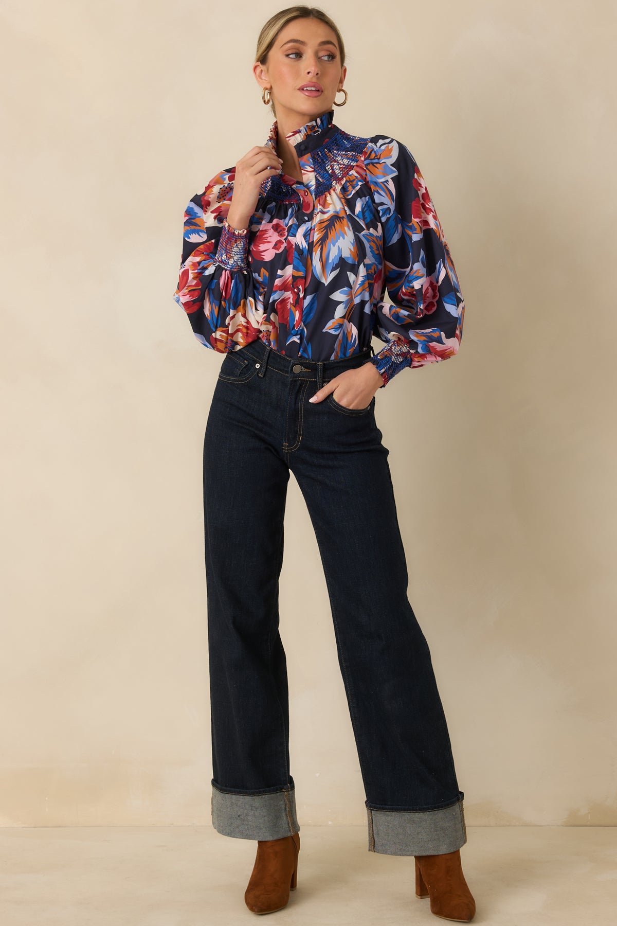 Deep navy cotton top with oversized pink, red, blue, orange, and ivory florals, a ruffled stand collar, and long blouson sleeves.
