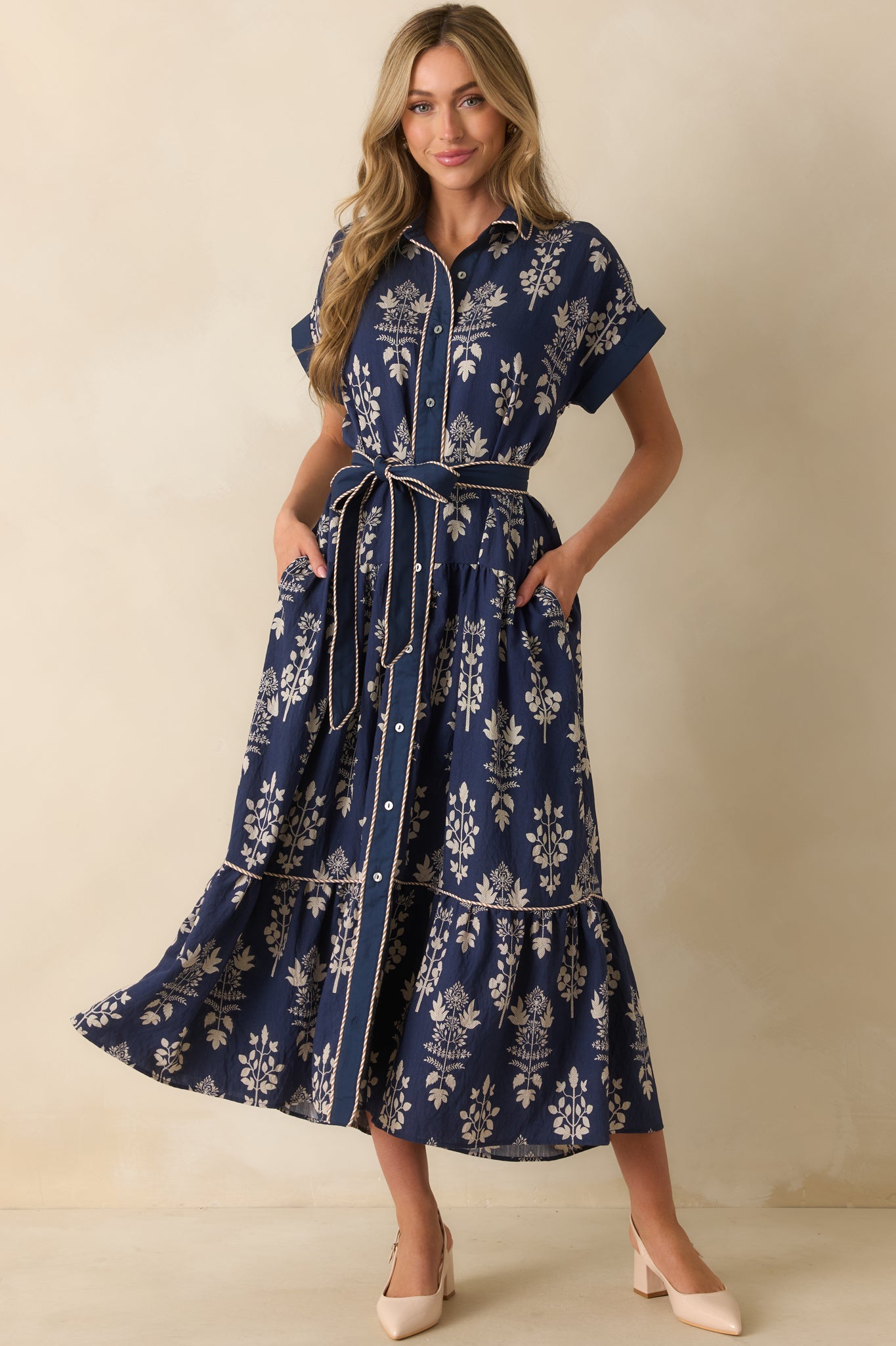 Floral navy dress featuring a button front, optional self-tie belt, and stripe contrast piping along the placket.