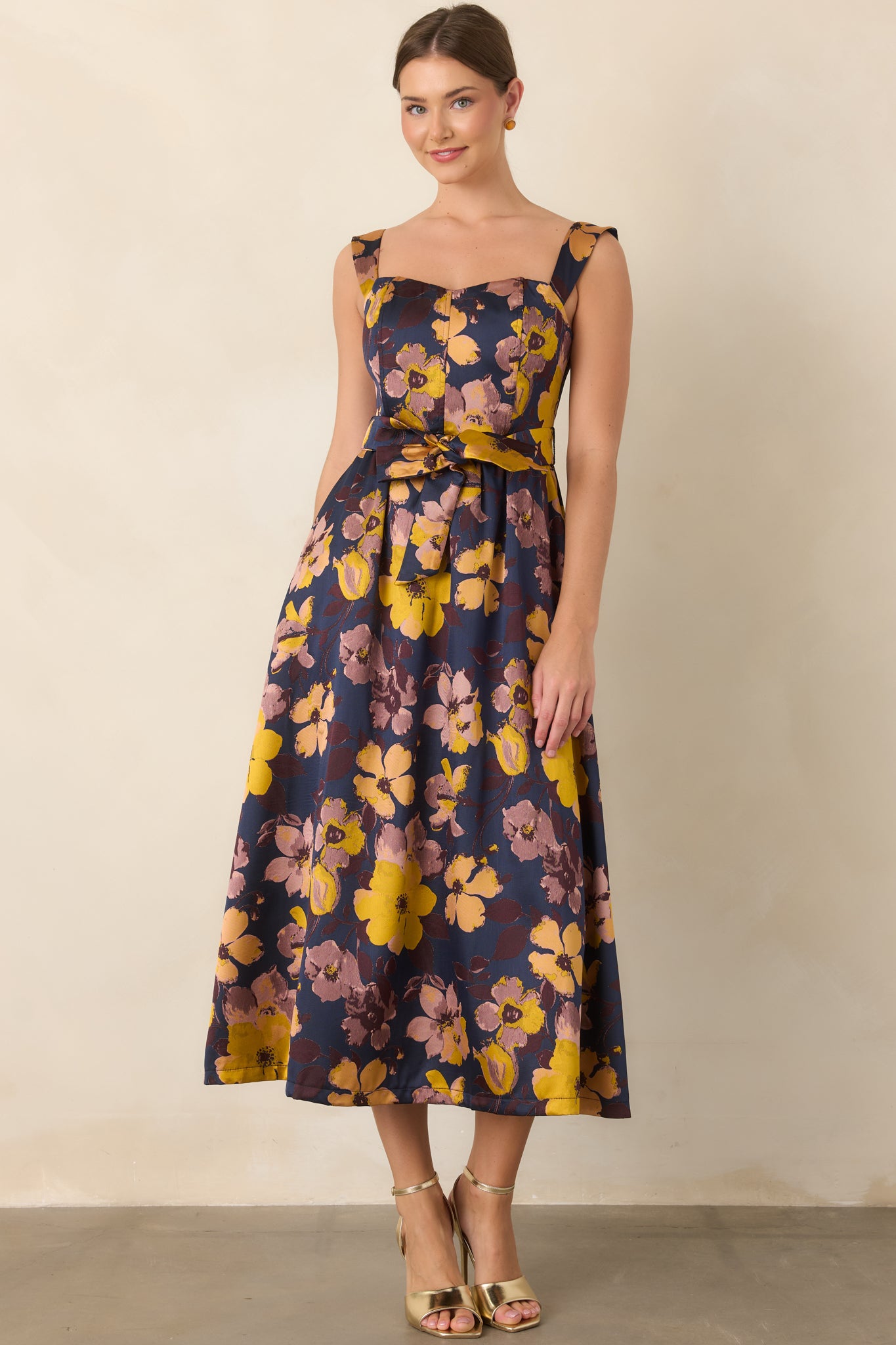 Navy floral dress highlighting the square neckline, cinched tie waist, and graceful flowing midi-length skirt.