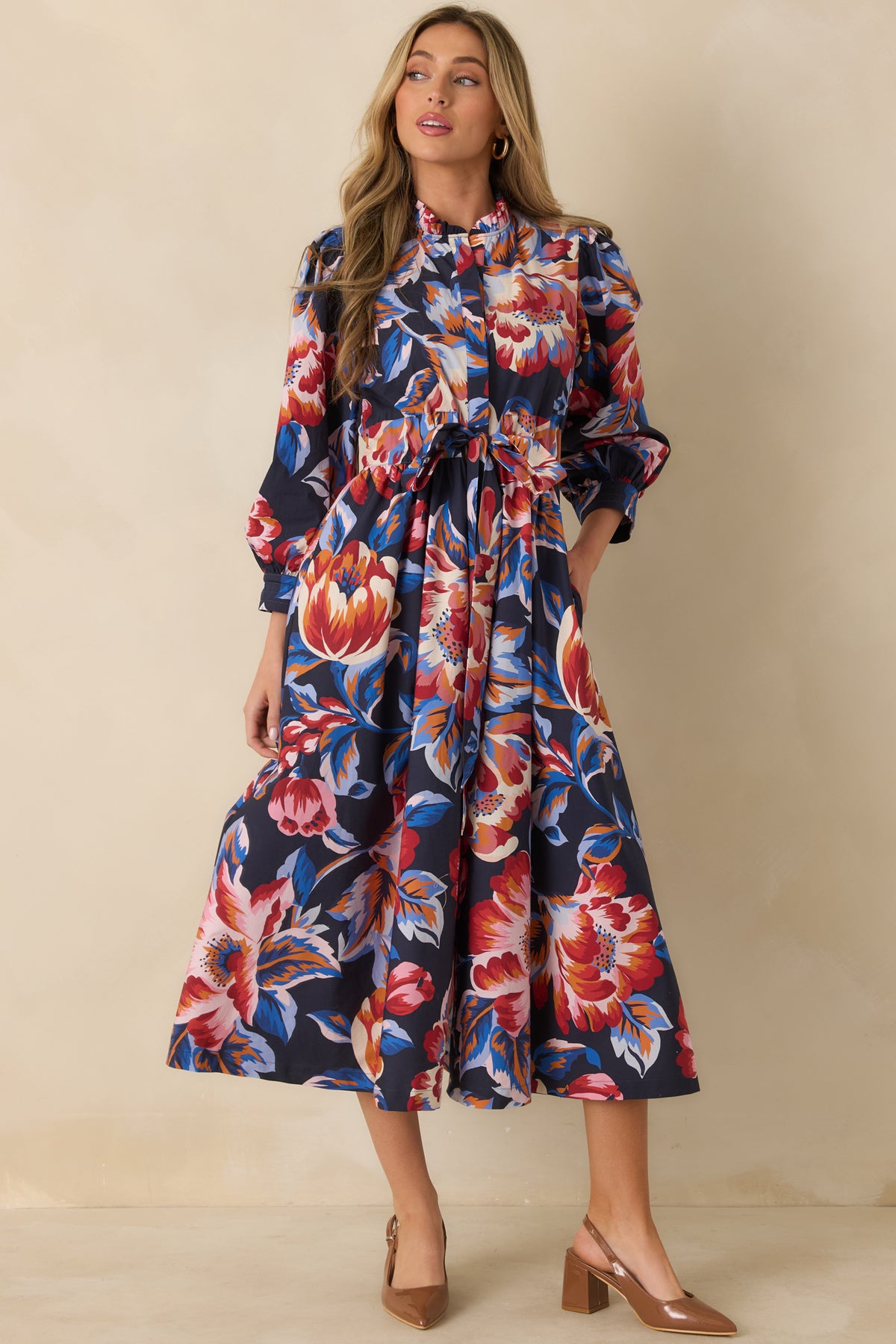 Deep navy floral dress with a gathered midi skirt, billowy sleeves, and practical side pockets.
