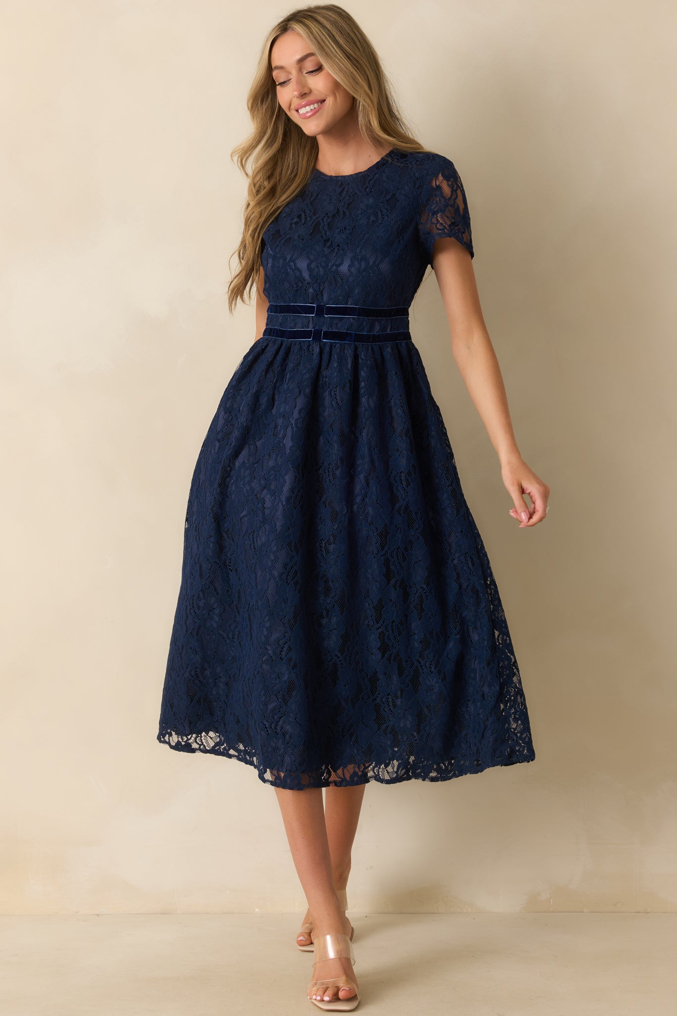 Navy floral lace dress with sheer detailing at the sleeves and a soft, flowing midi-length skirt.