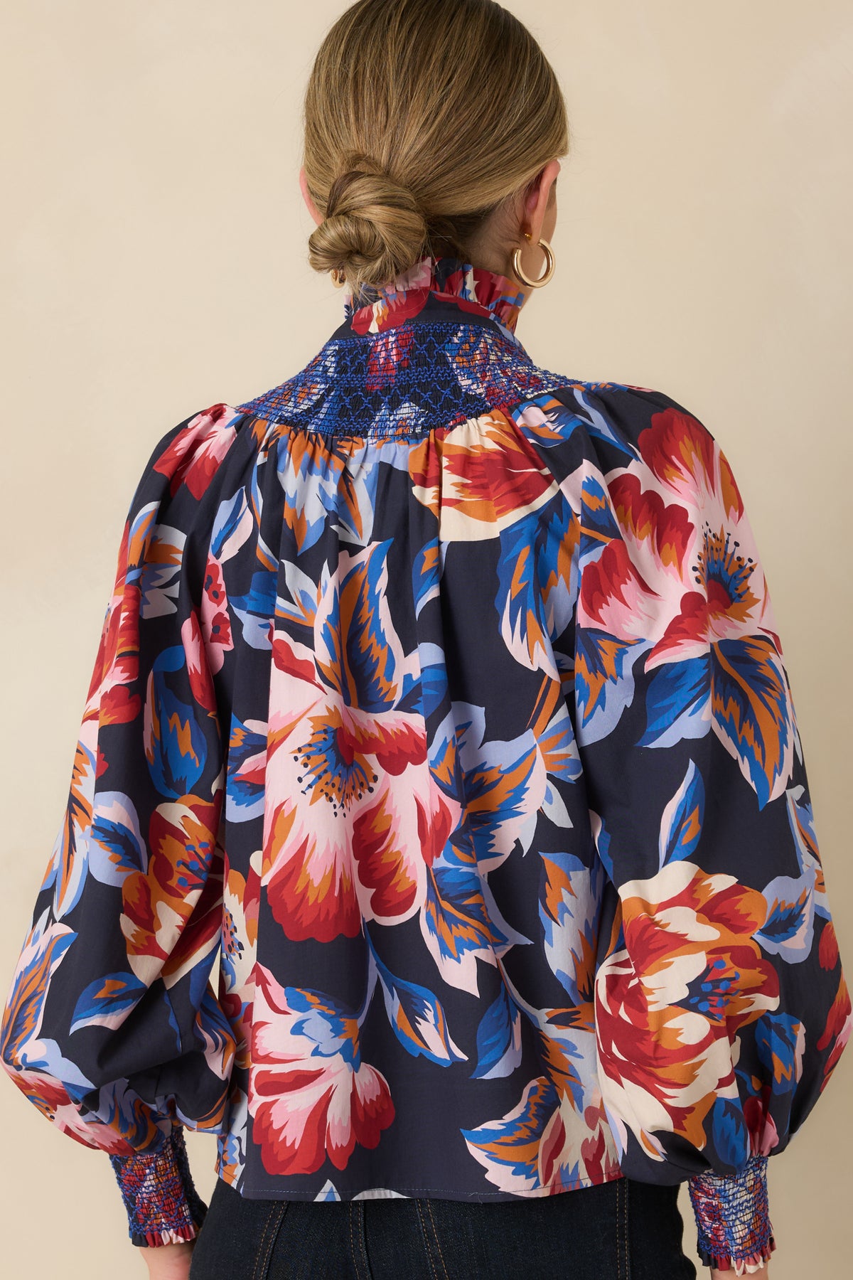 Rear of the deep navy floral cotton top showing the blue smocked back yoke and gathered blouson sleeves with smocked cuffs.
