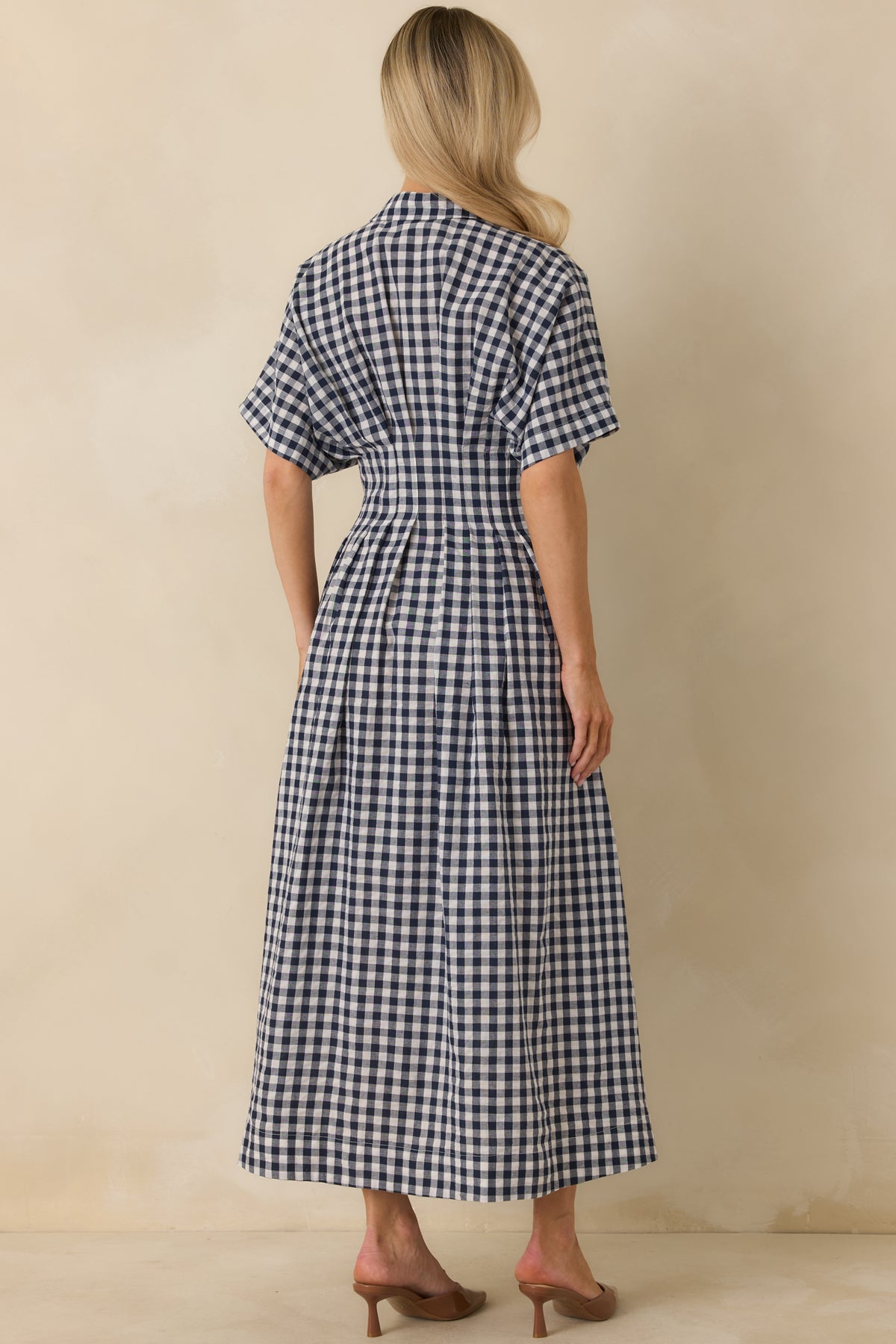 Back view of navy gingham midi dress with ivory checks, turned sleeve cuffs, pleated waist, and functional side pockets.