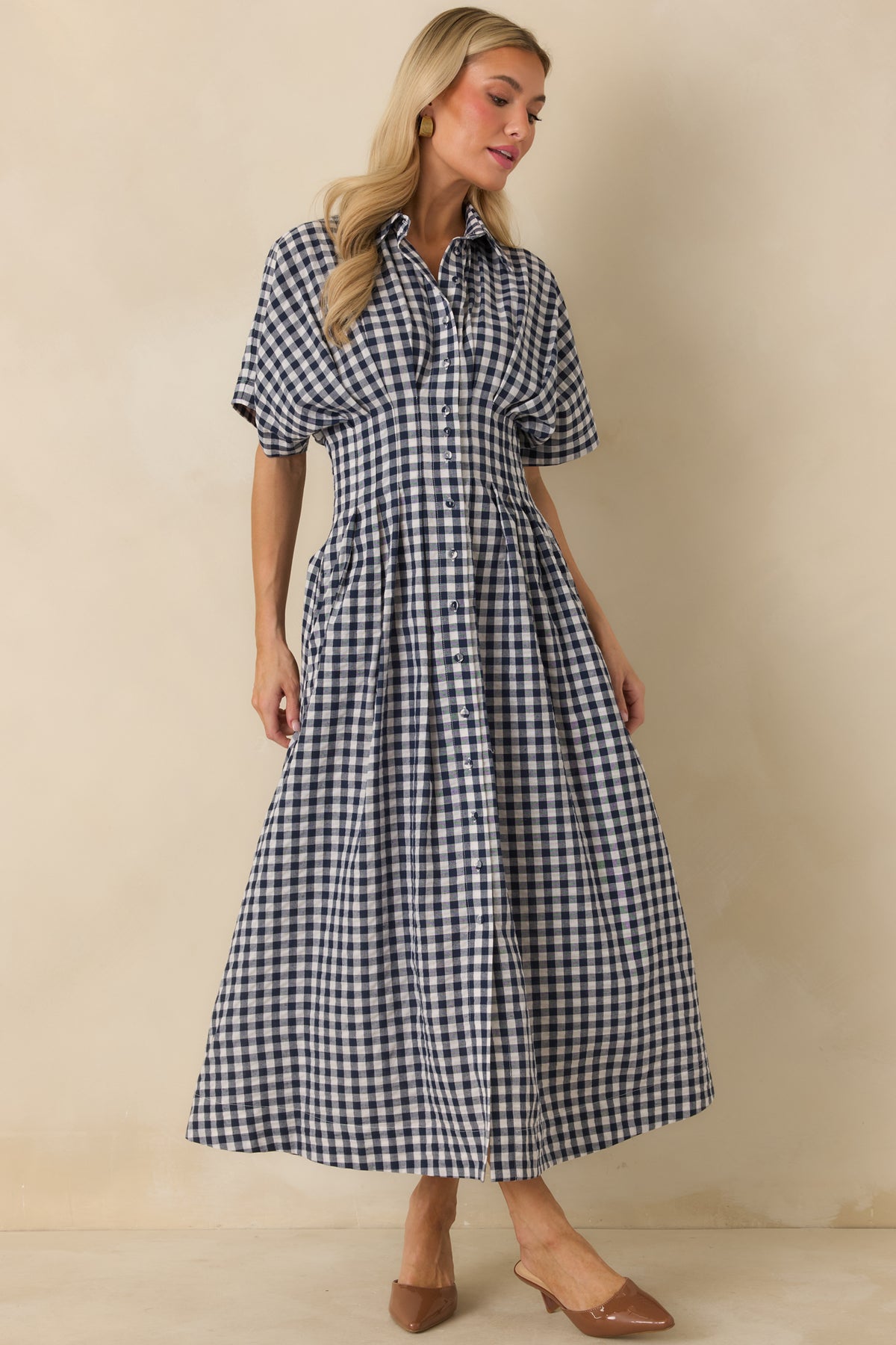 Navy gingham midi dress with ivory checks, turned sleeve cuffs, pleated waist, and functional side pockets.
