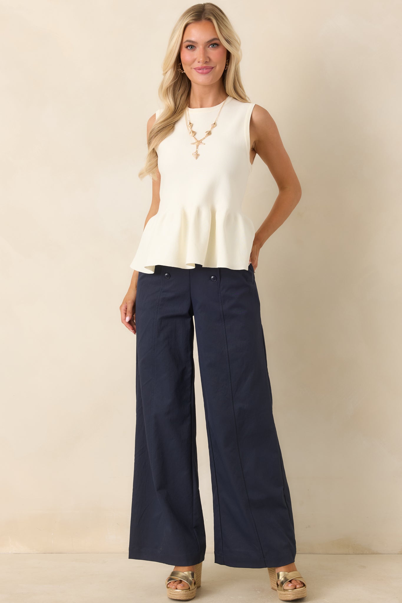 High-rise navy wide-leg trousers with functional front buttons, back welt pockets, and polished tailoring.
