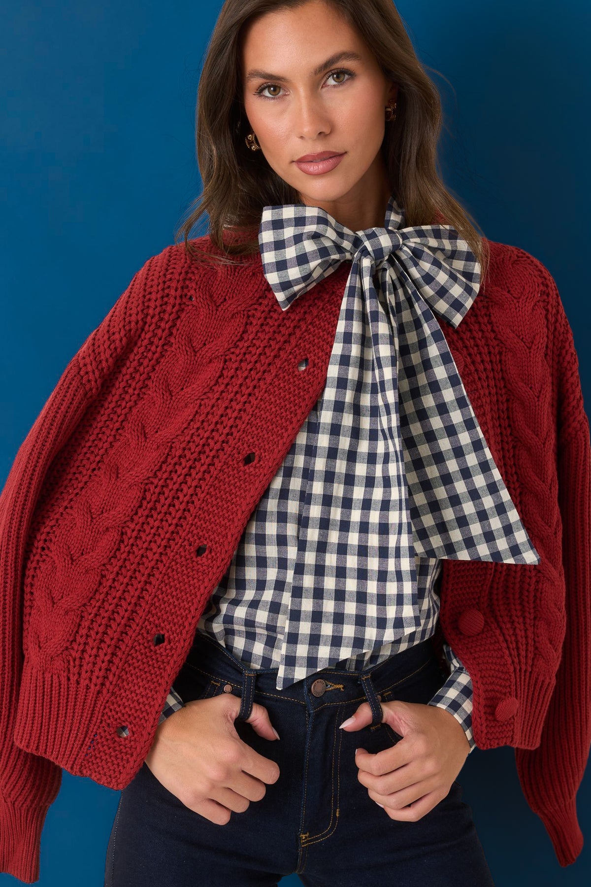 Navy and ivory gingham blouse showcasing the oversized neck tie and concealed front button placket with blue background.