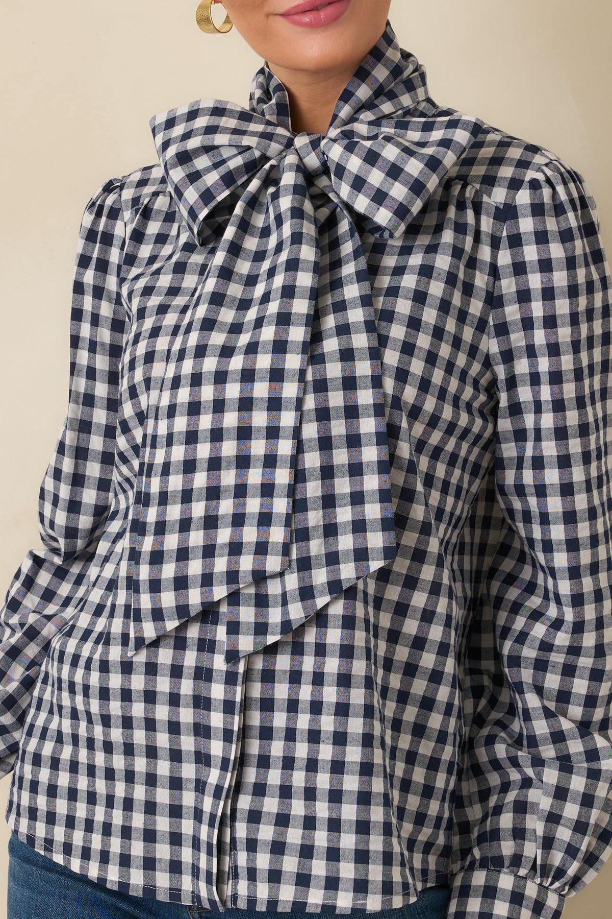 Close-up of the navy and ivory gingham pattern, oversized neck tie, and concealed front button placket.