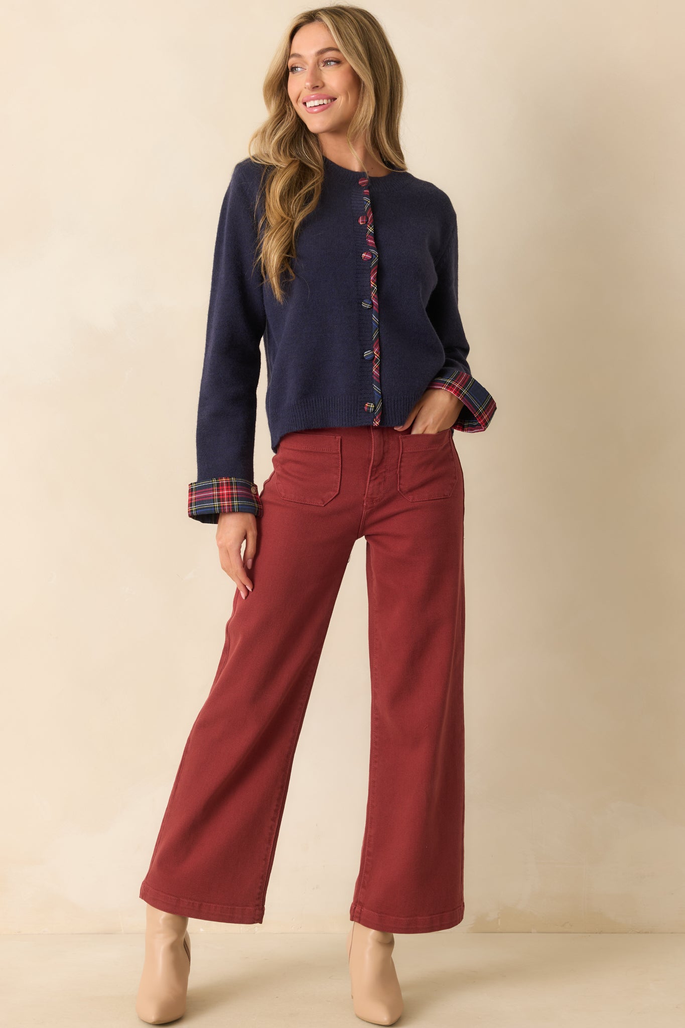 Navy knit cardigan with contrast tartan placket, functional button closure, and subtle plaid detailing on the cuffs.