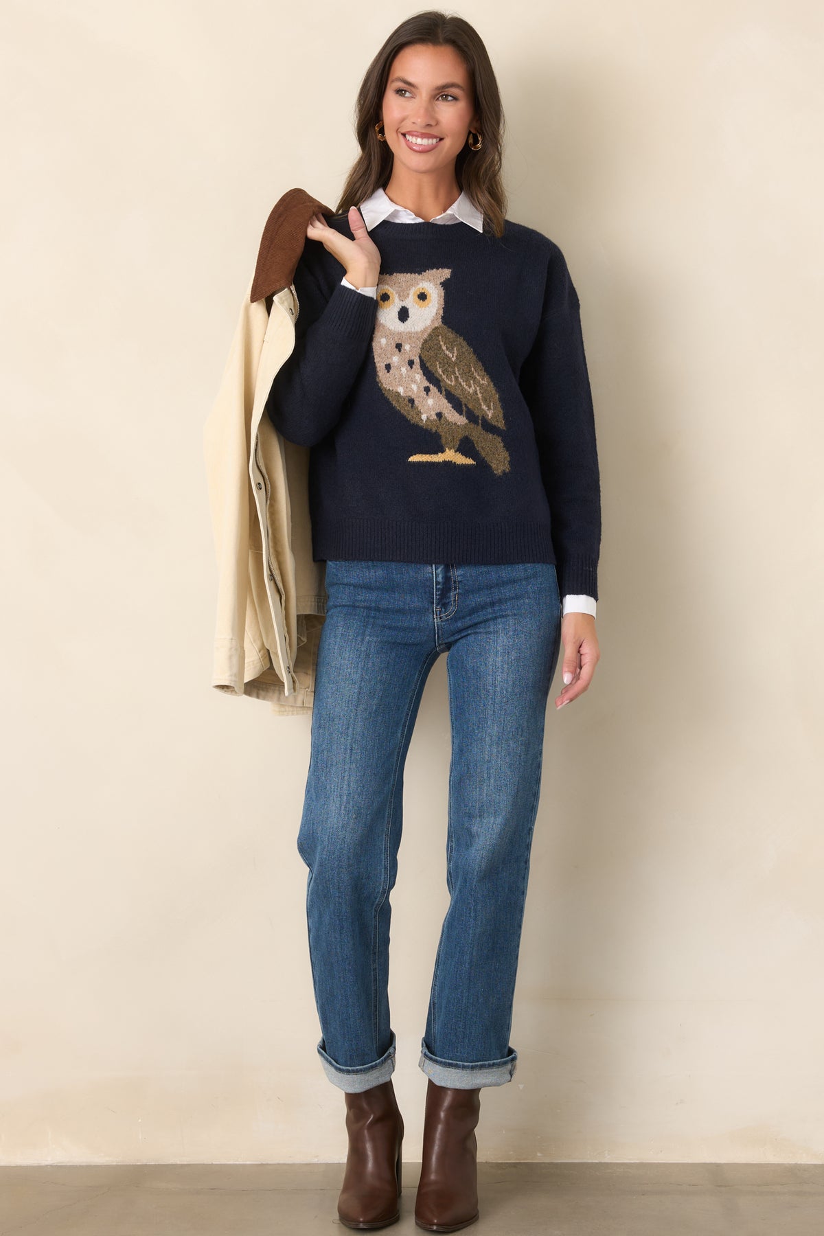 Deep navy knit pullover featuring a wide-eyed owl graphic in taupe, ivory, olive, and golden yellow, with a crew neckline and long sleeves.