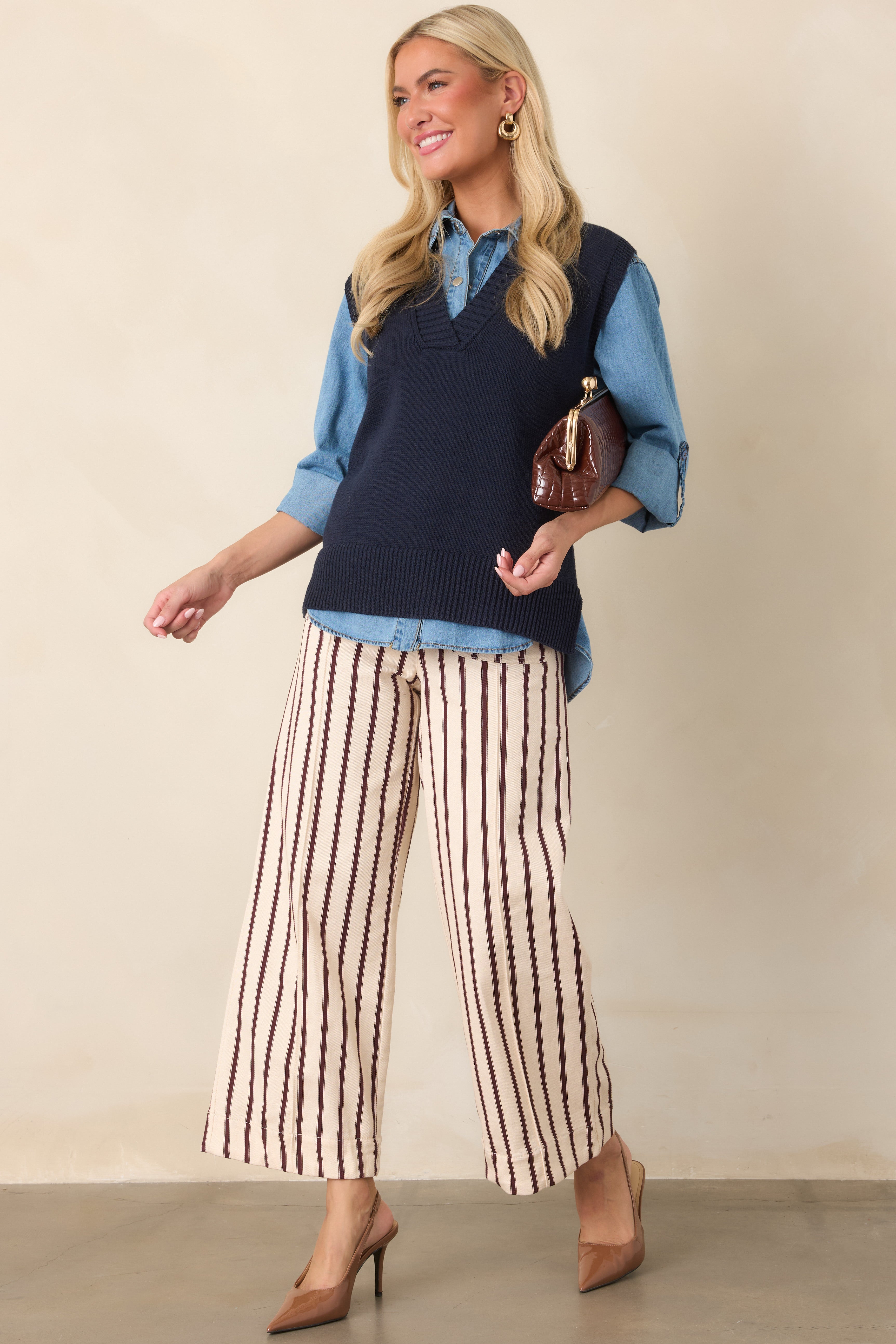 Navy knit sweater vest with a sleeveless silhouette, ribbed V-neckline, wide ribbed hem, and relaxed, refined shape.
