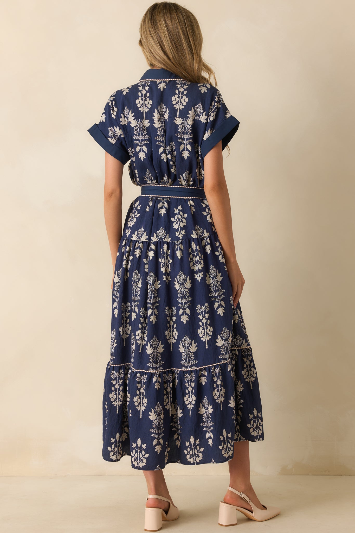 Rear view of the navy maxi dress highlighting the smooth back, short cuffed sleeves, and tiered skirt.