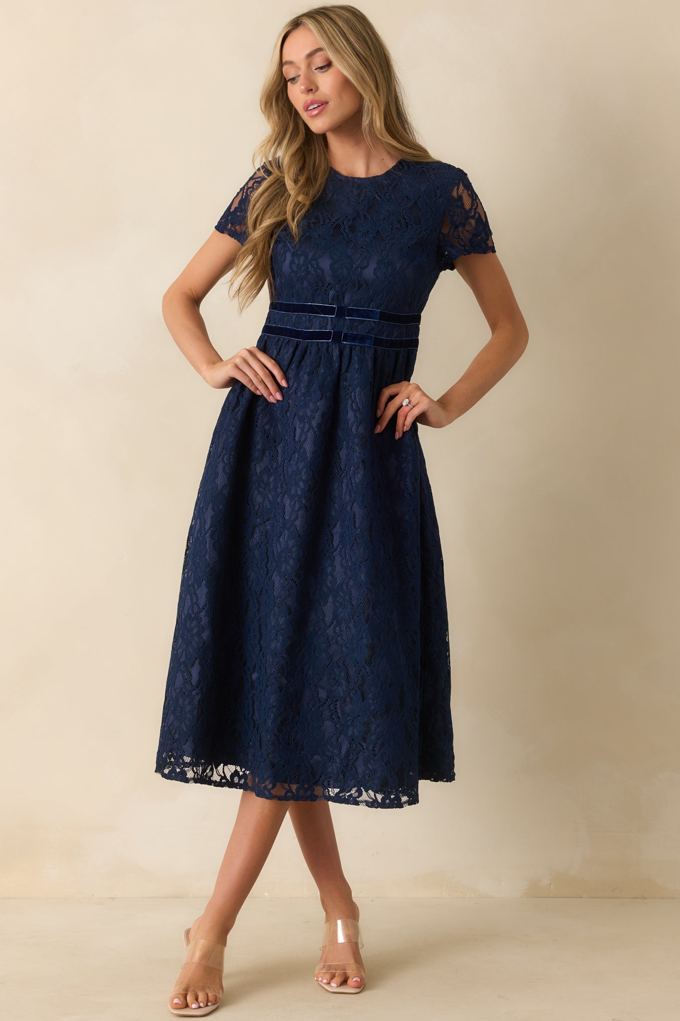 Navy midi dress with a sheer floral lace overlay, round neckline, and fitted bodice trimmed with three velvet waist bands.
