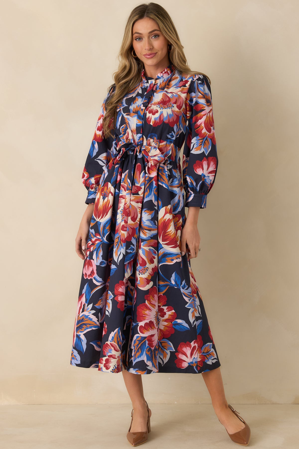 Deep navy cotton midi dress with oversized multicolor florals, a ruffled stand neckline, and billowy sleeves.