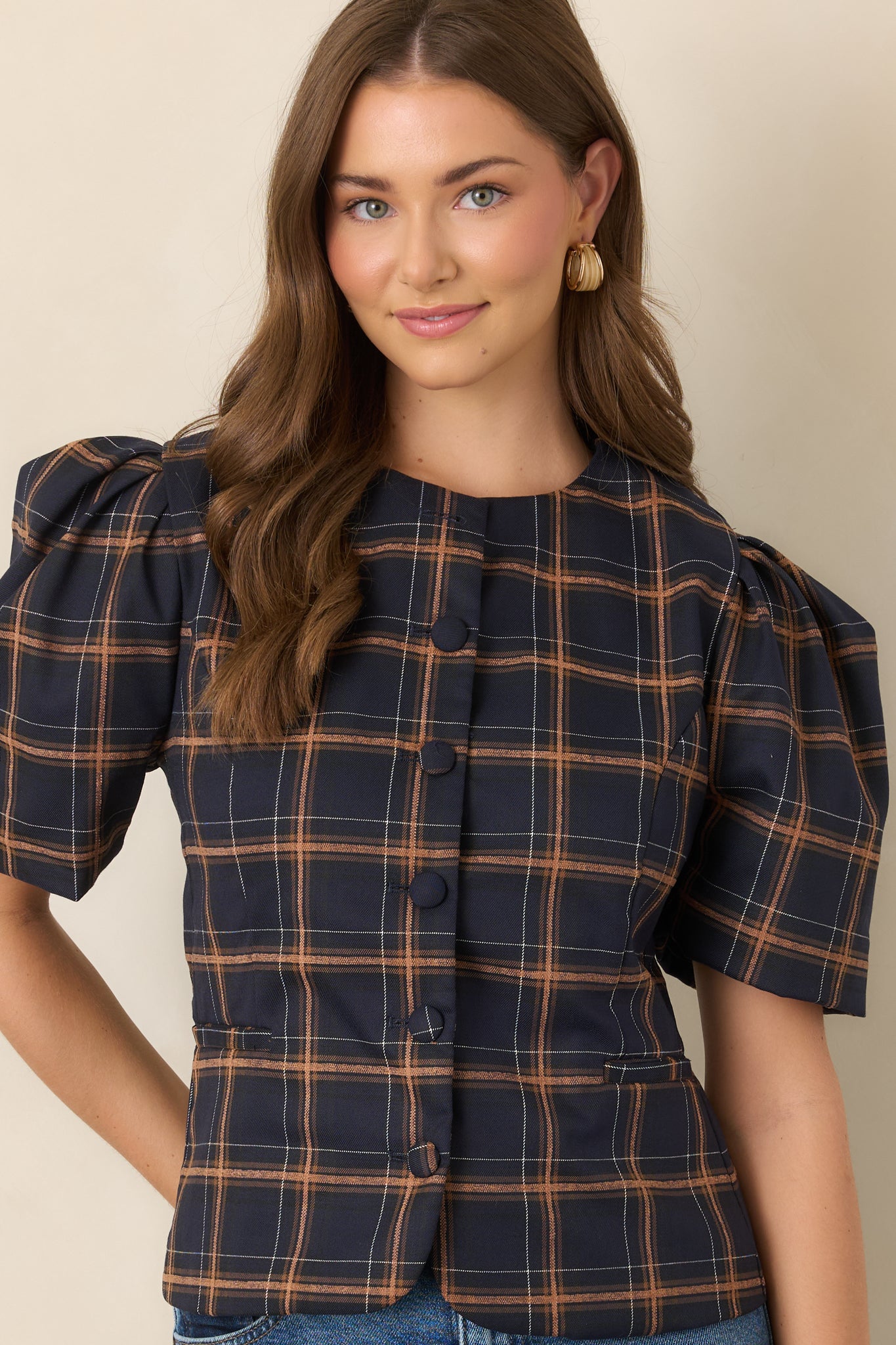 Close view of the navy, camel, and ivory plaid top highlighting the rounded neckline, structured woven texture, and tailored waistline.