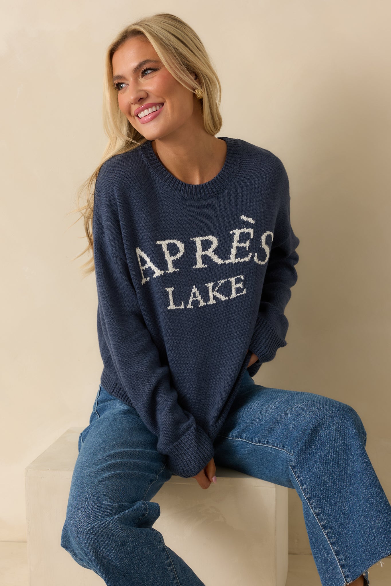 Full front-facing perspective showing the overall silhouette, ribbed cuffs, and white lettering on the navy pullover.