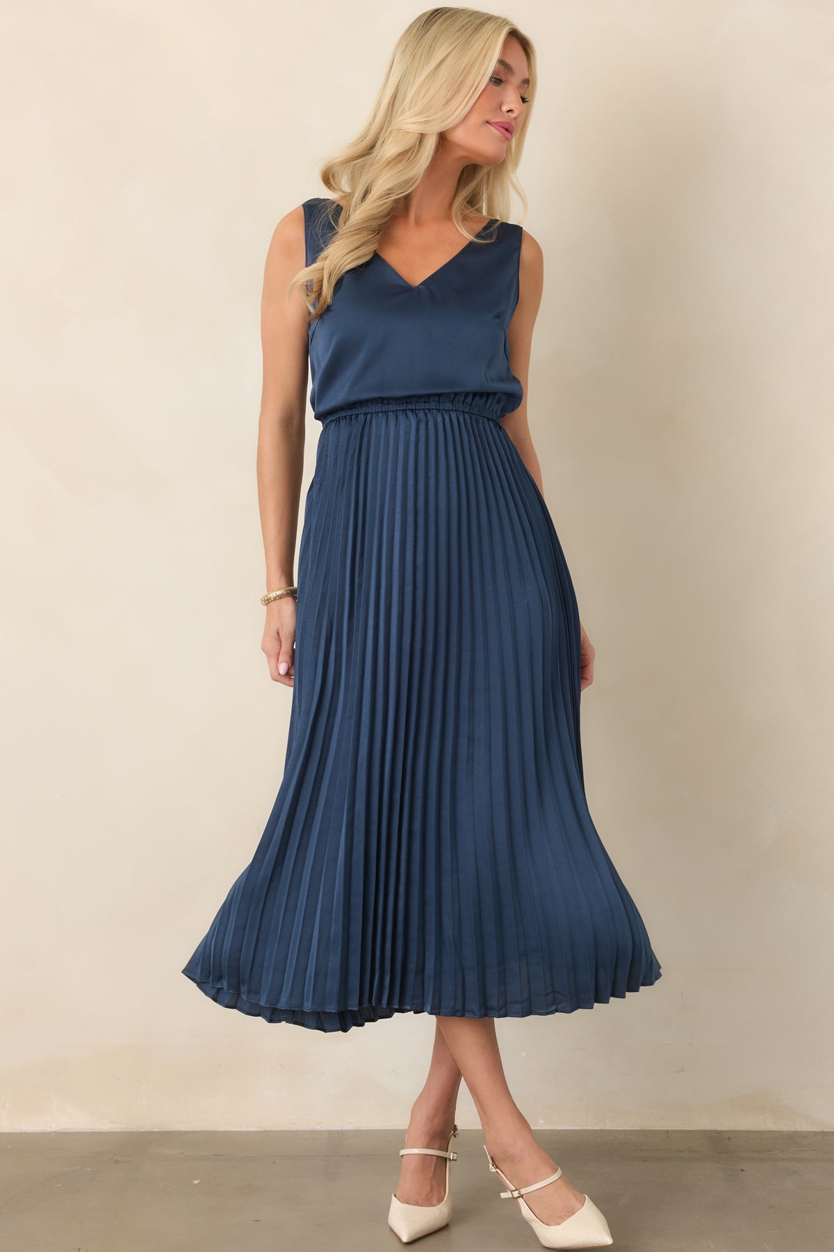 Navy satin midi dress featuring a V-neckline, elastic waist, and flowy pleated skirt.