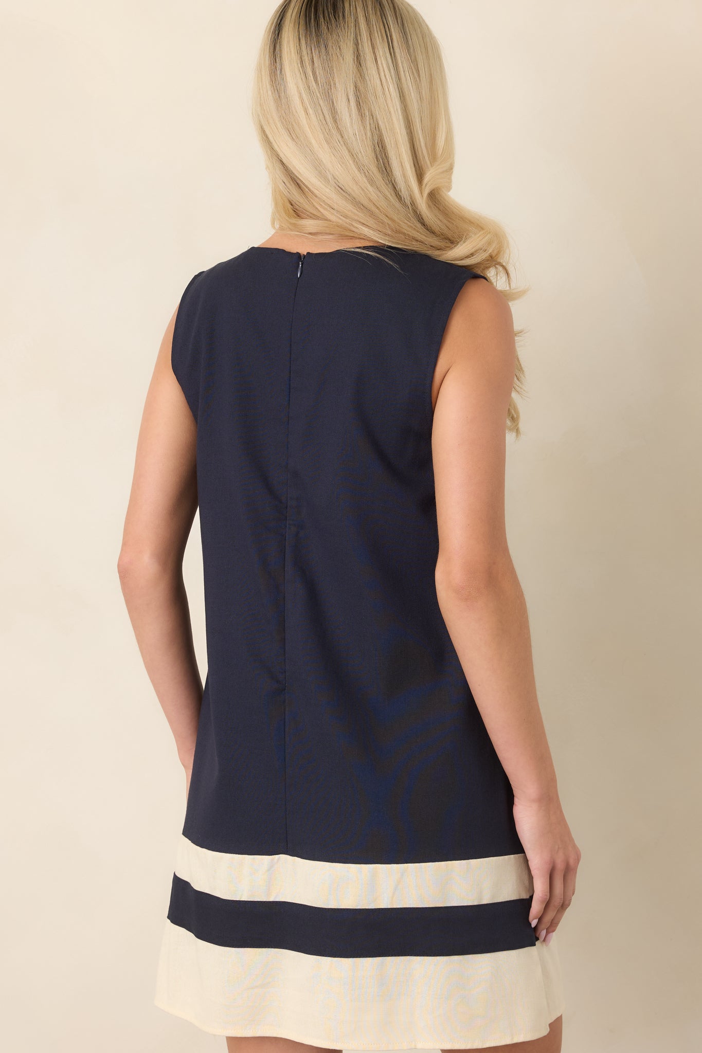 Rear view of the navy shift mini dress showcasing the relaxed silhouette, sleeveless design, round neckline, and concealed back zipper.