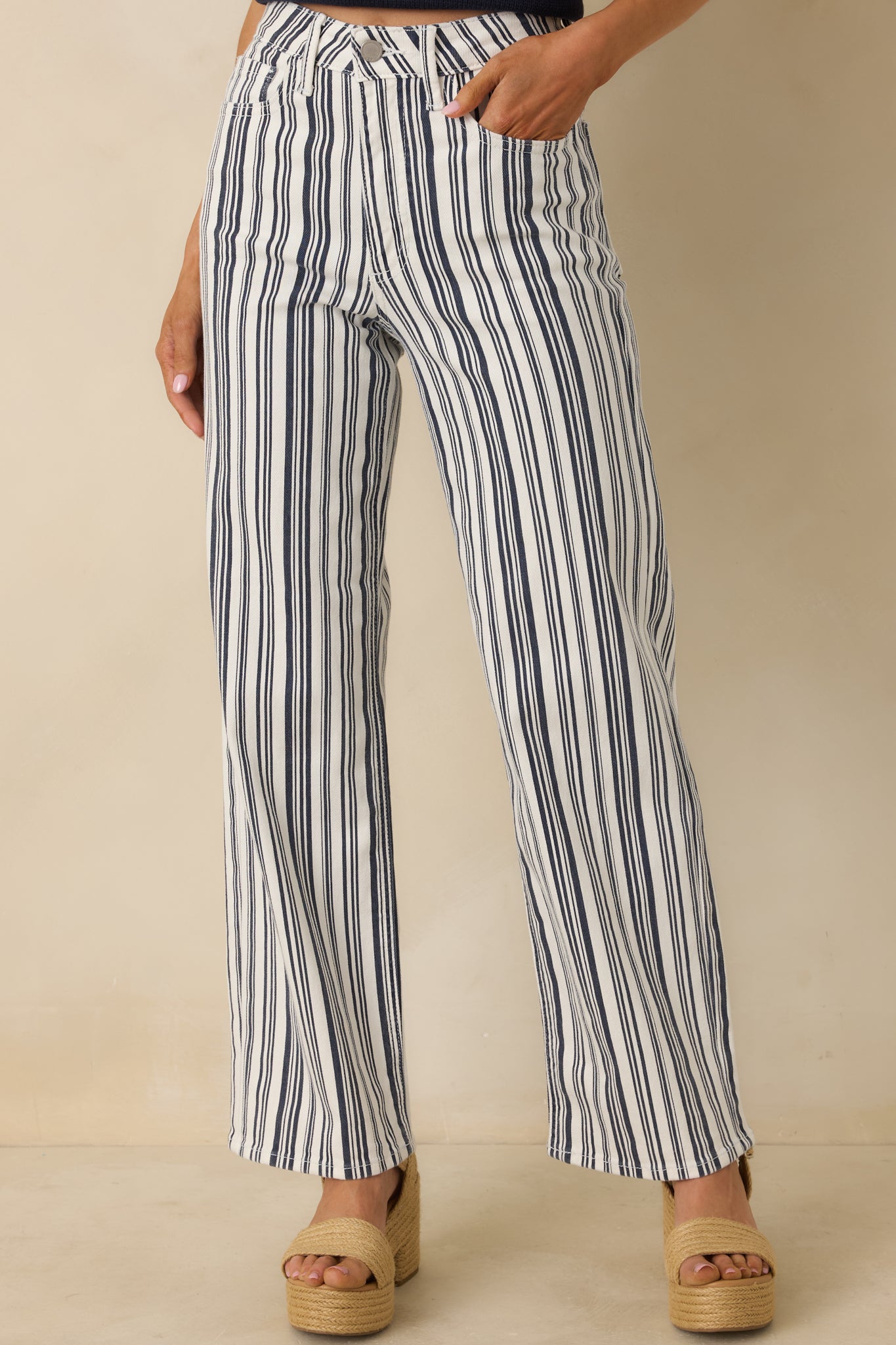 Navy striped wide-leg pants highlighting the structured high-rise waistband with button and zip closure.