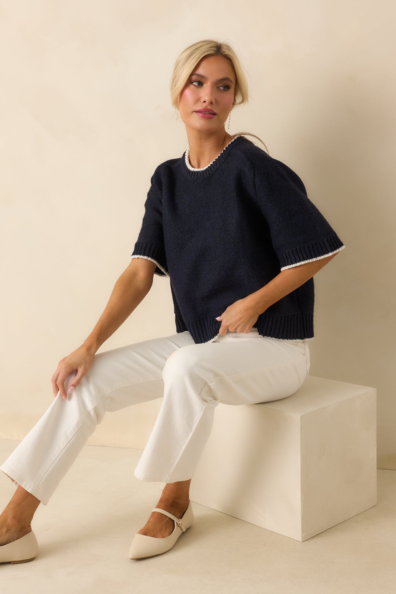 Navy sweater featuring ivory contrast trim along the neckline and sleeves.