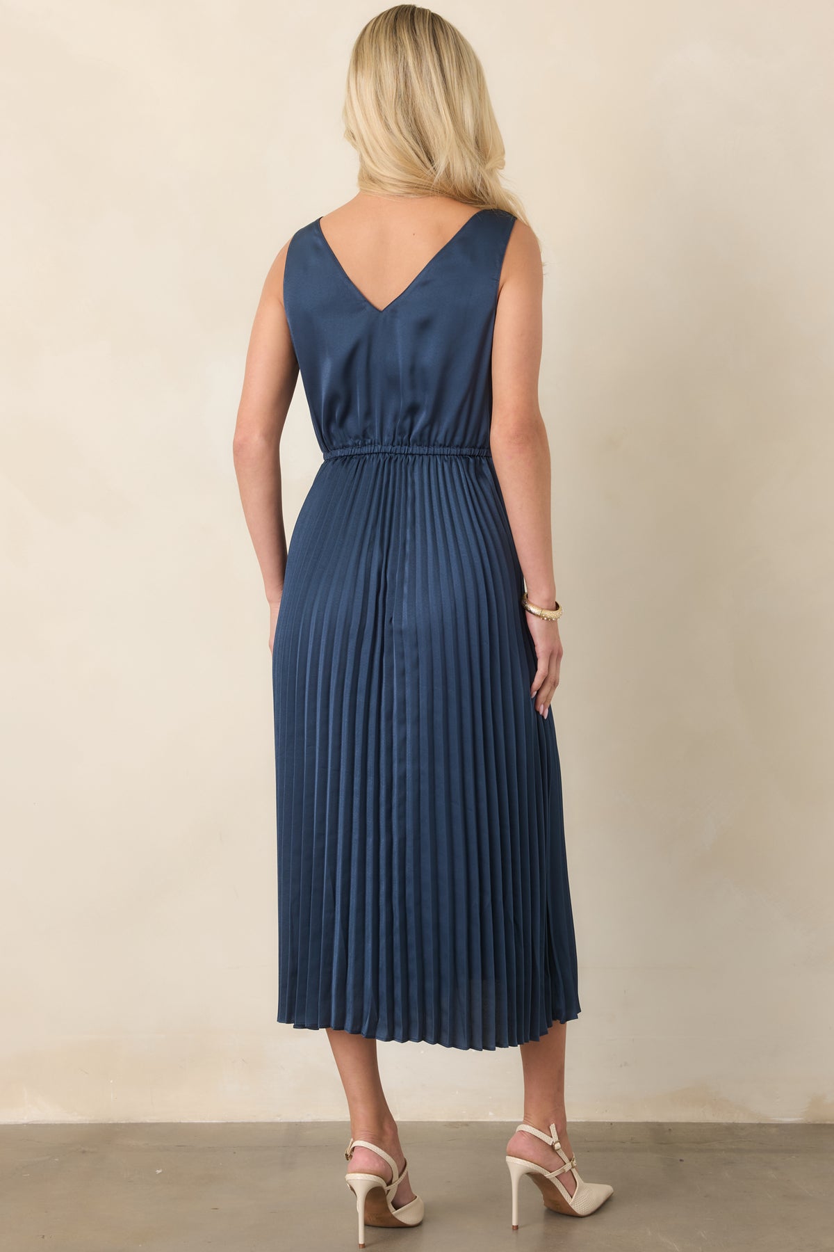 Rear of the navy two-piece set showing the cropped open-knit sweater and flowy pleated satin dress.