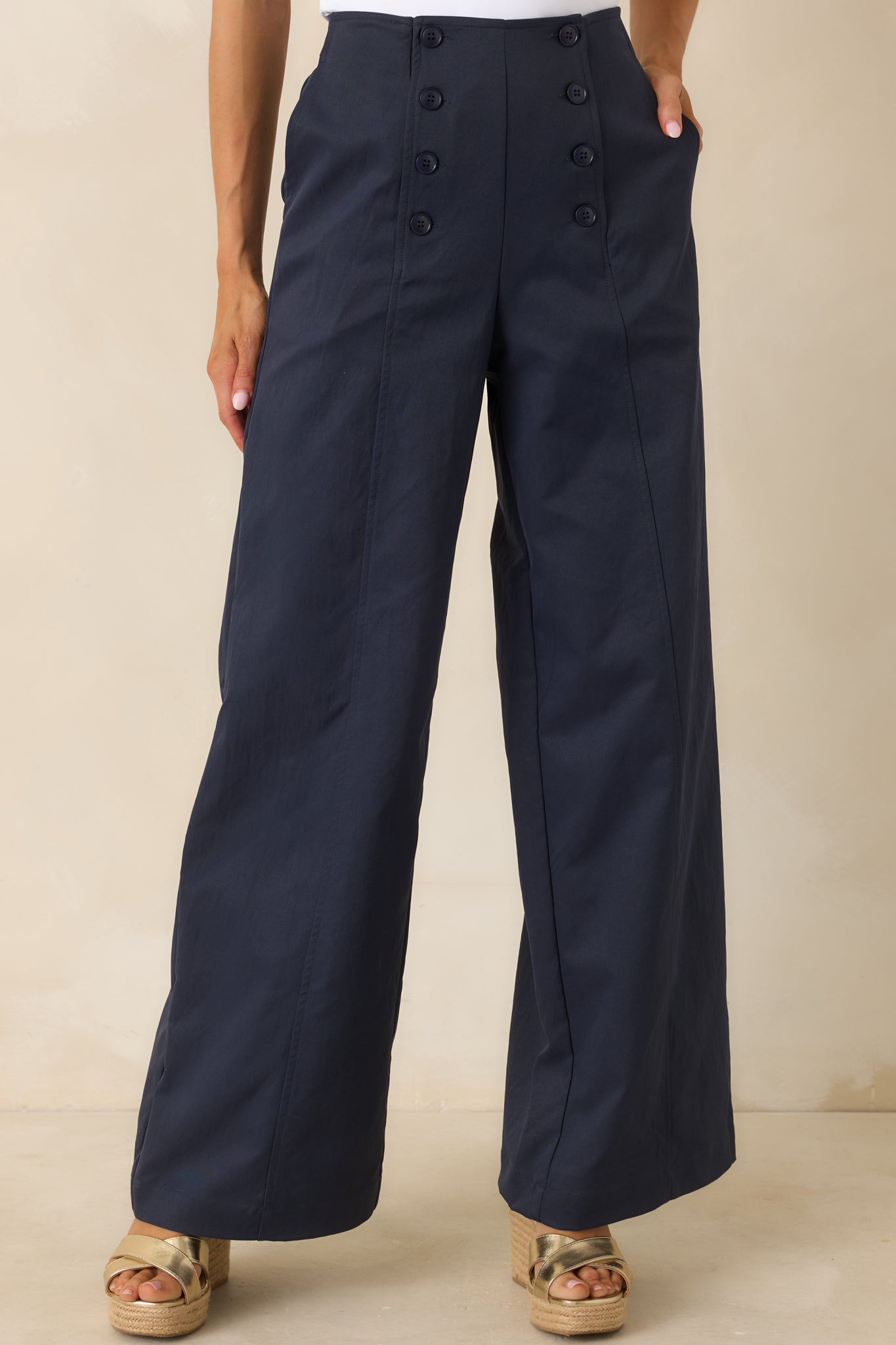 Navy wide-leg pants featuring a smooth fabric finish, high-rise waist, and front closure details.