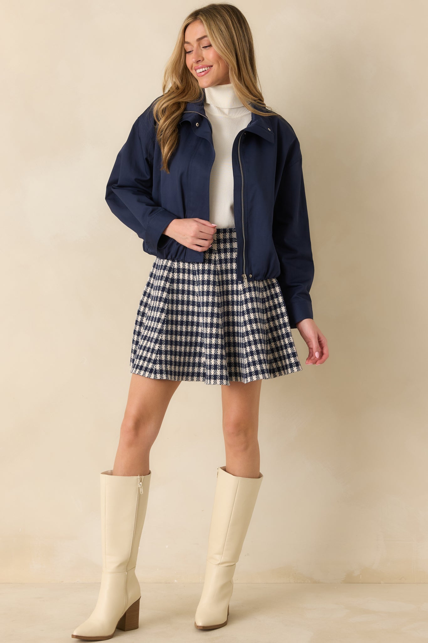 Navy woven bomber jacket showing smooth fabric, elasticized back hem, and slightly cropped fit.