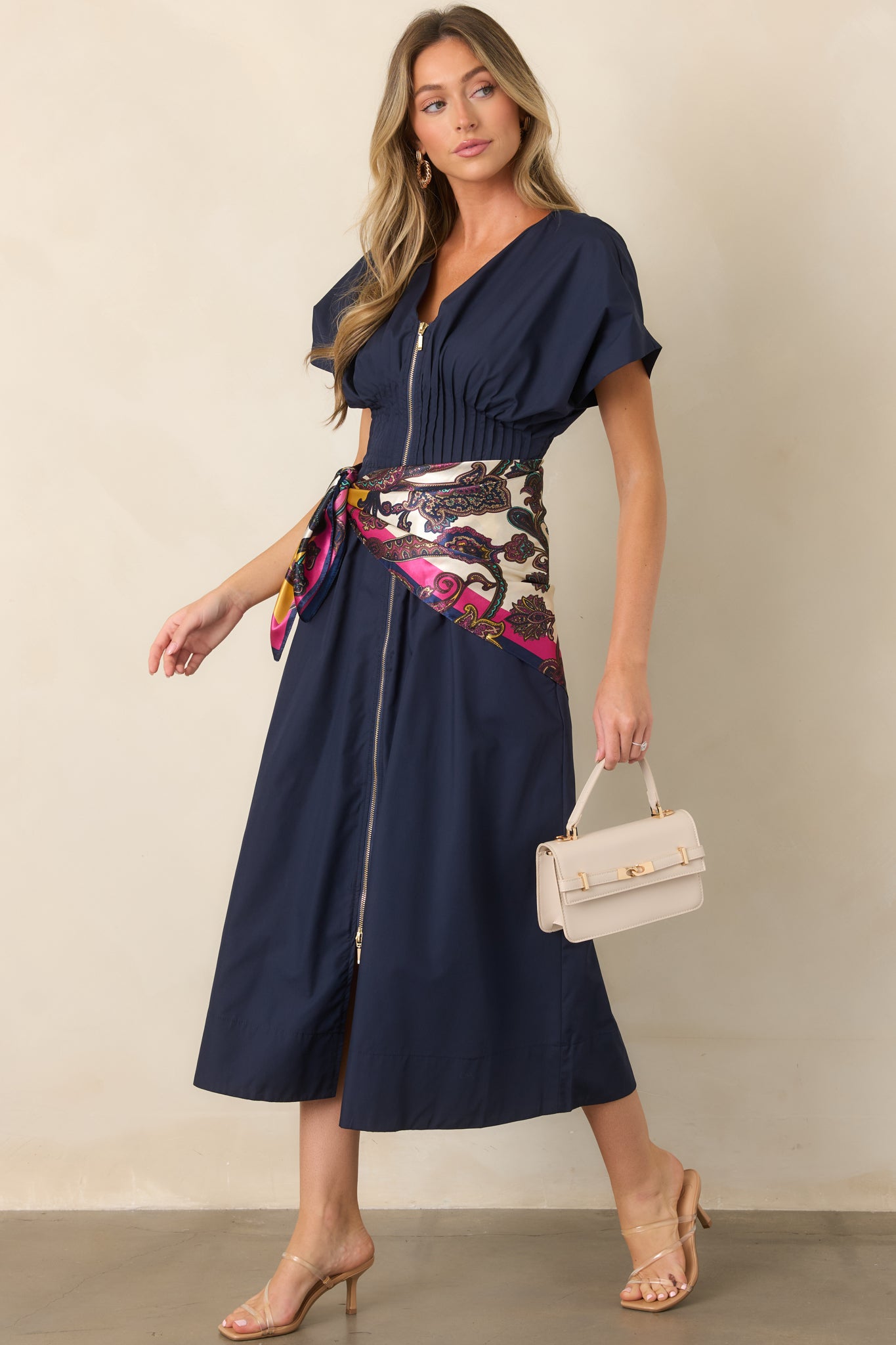 Navy woven maxi dress featuring a V-neckline, front zip closure, short sleeves, and a wide smocked waistband with ruffled trim.