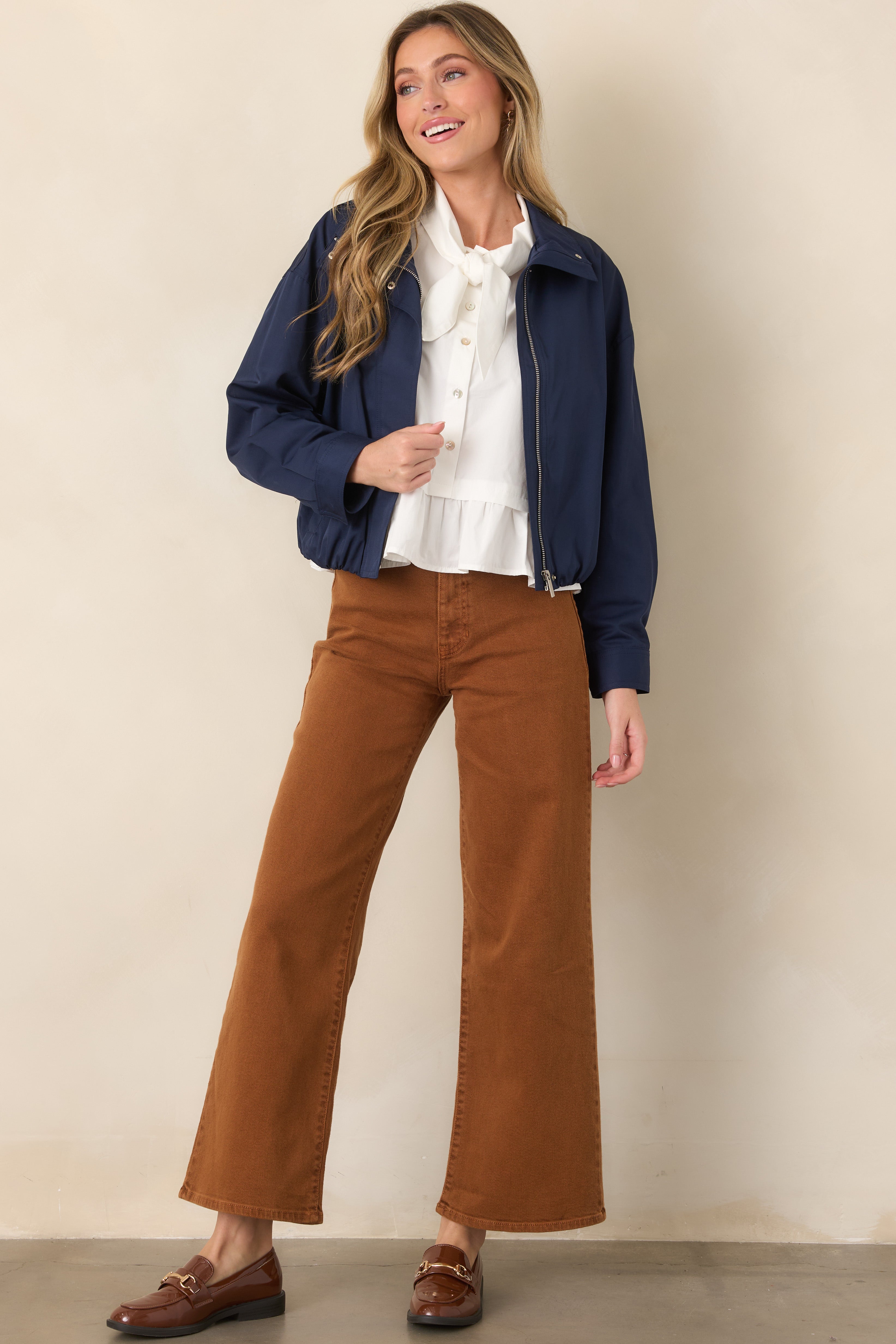 Navy zip-front jacket with a structured stand collar, dropped shoulders, long sleeves, and softly gathered elasticized hem.