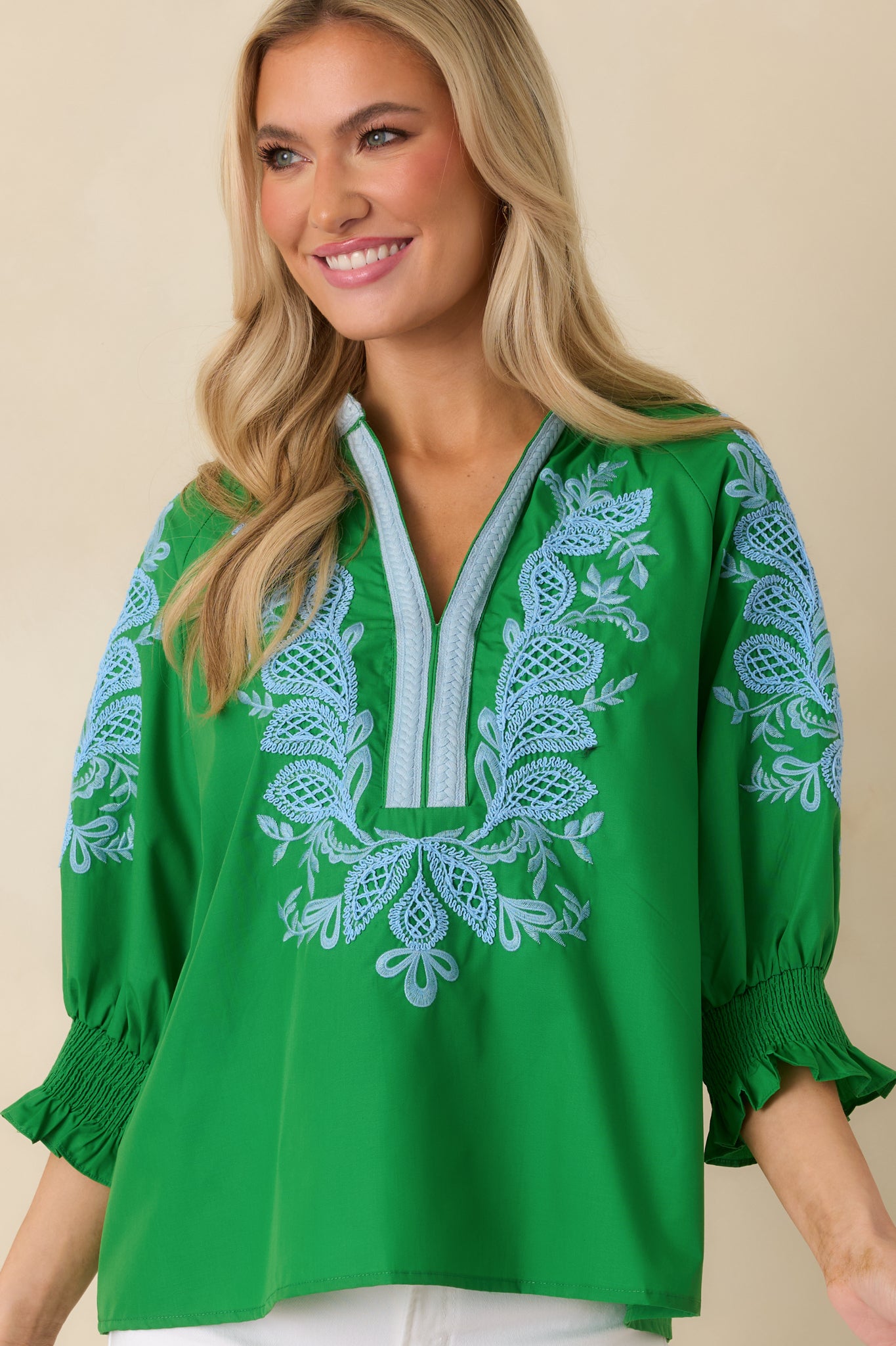 Cropped detail of the neckline and upper chest showing contrast trim and fine embroidery.