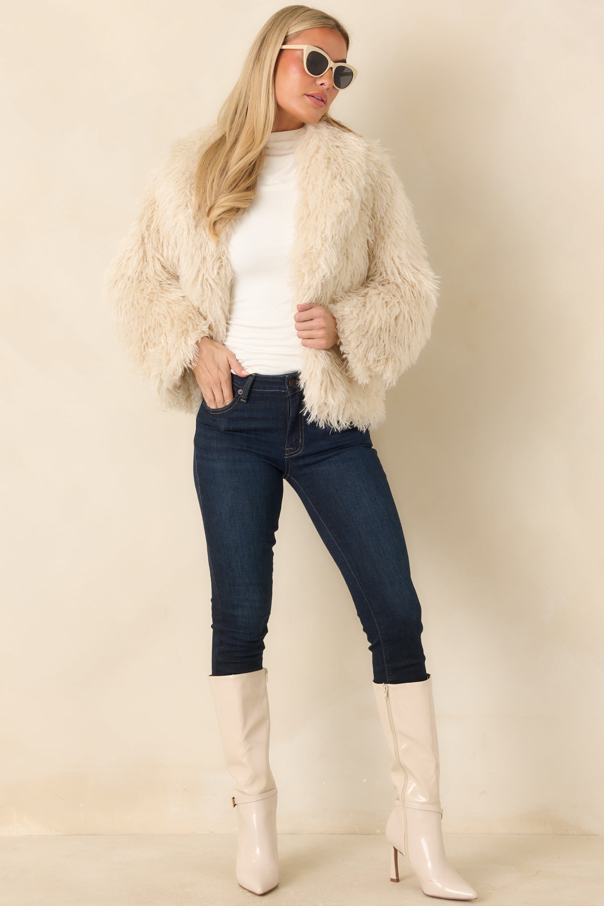 Neutral-toned plush jacket with long wavy fibers, an open front, long sleeves, and a relaxed hip-length silhouette.