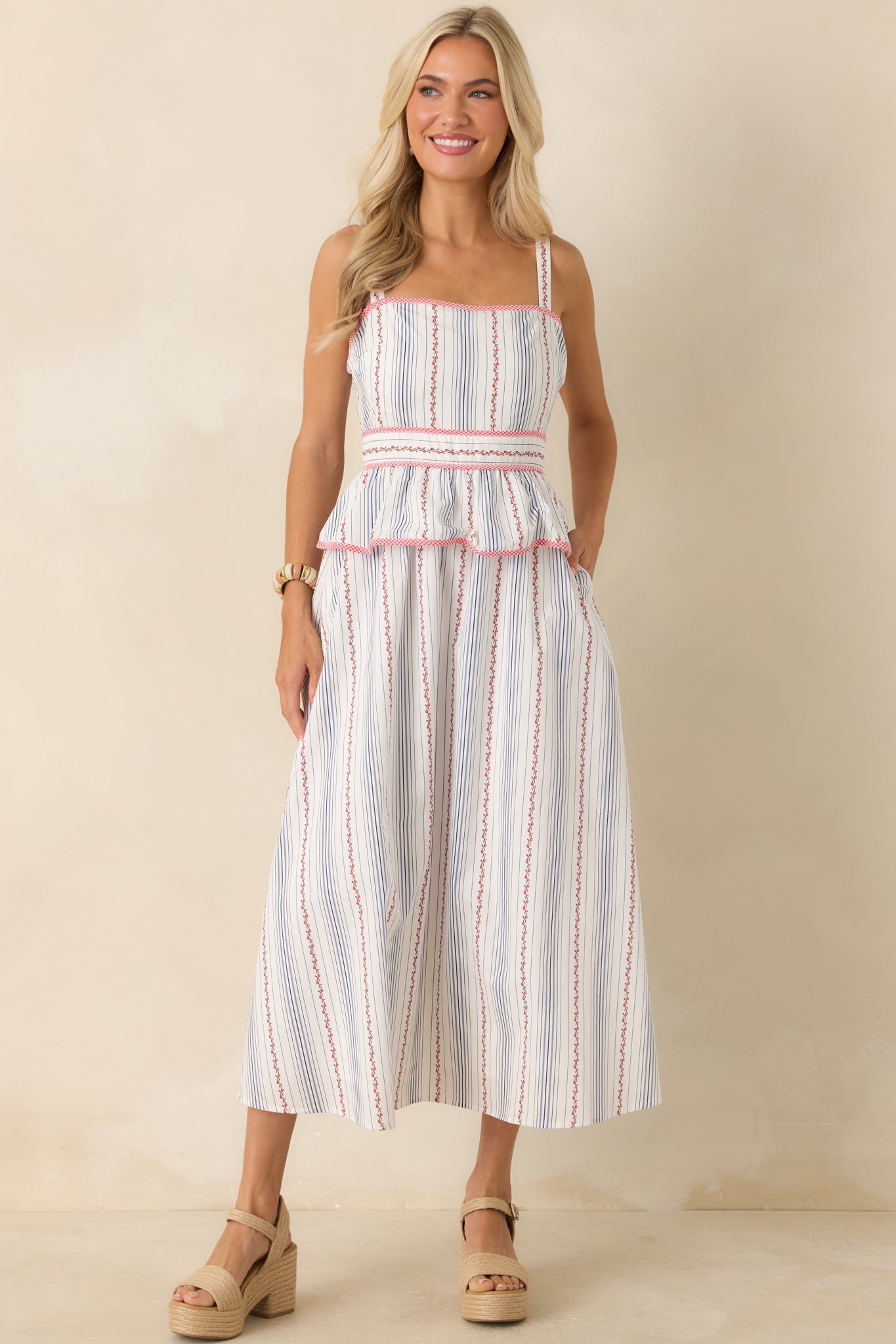 Nostalgic-inspired floral stripe dress featuring red gingham trim, a flattering peplum waist, and a polished midi length.