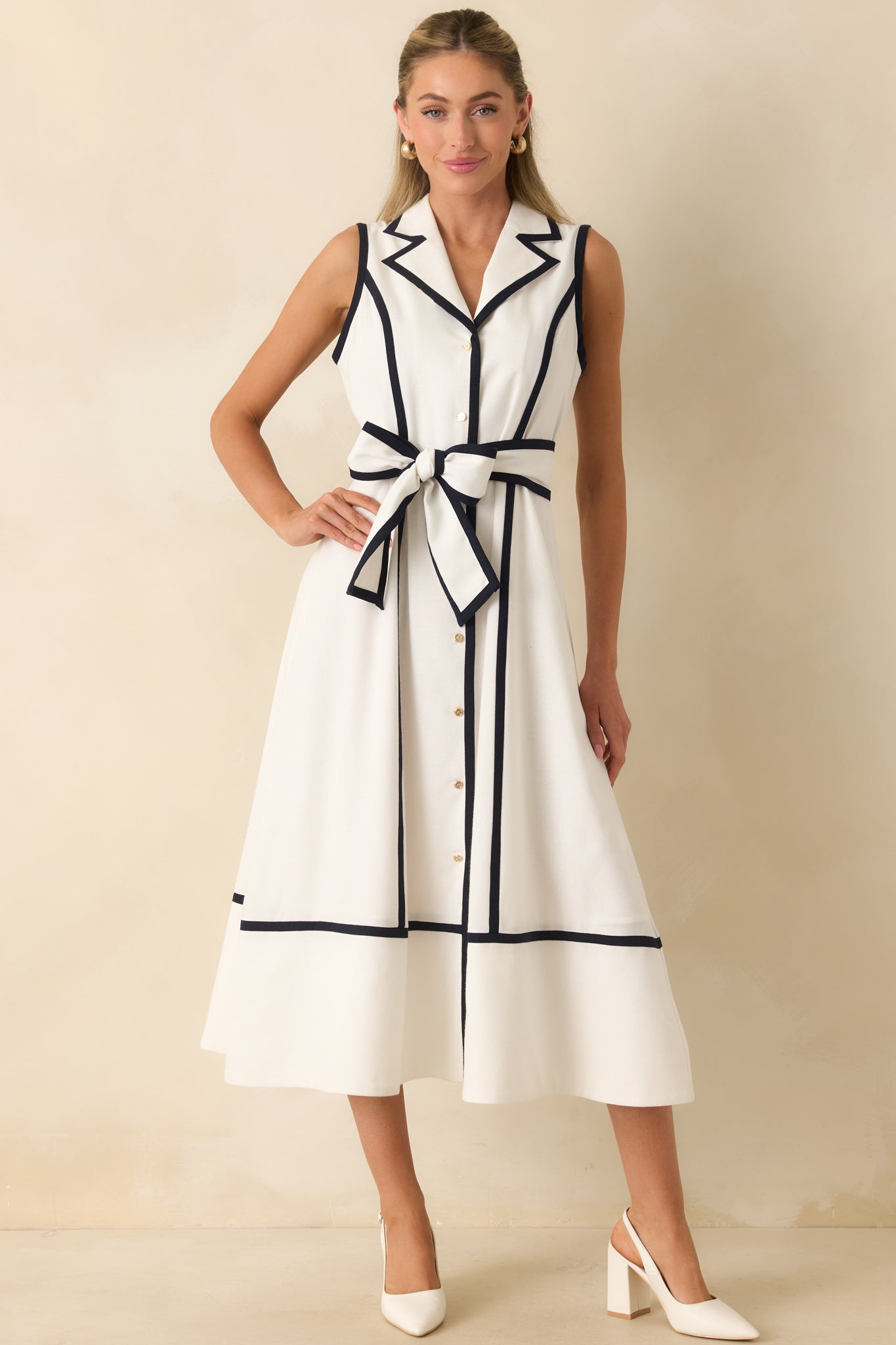 Midi dress designed with a polished notched collar, button-front closure, and navy piping along the seams and hem.