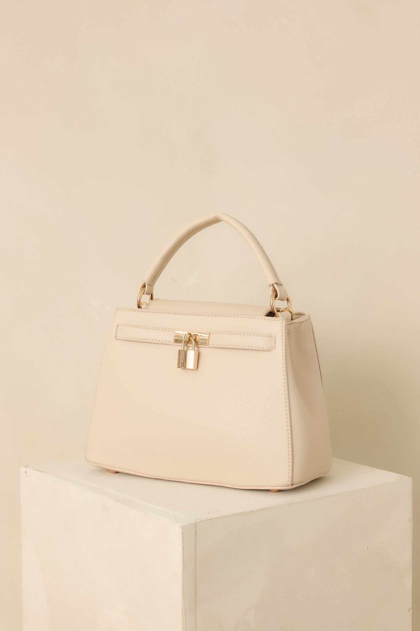 Full view of the nude faux leather handbag featuring a structured silhouette, top handle, and removable shoulder strap.