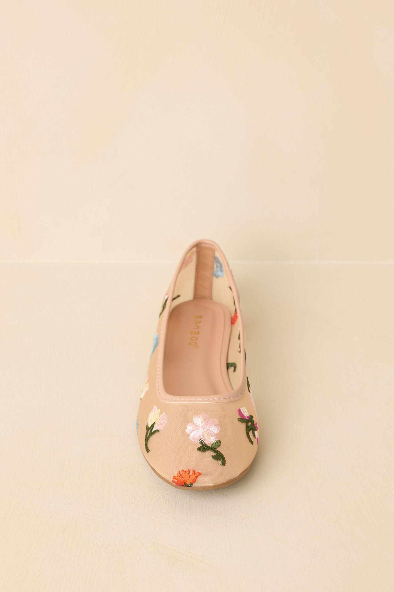 Nude mesh ballet flats with floral embroidery displayed on a beige background, showcasing slip-on design