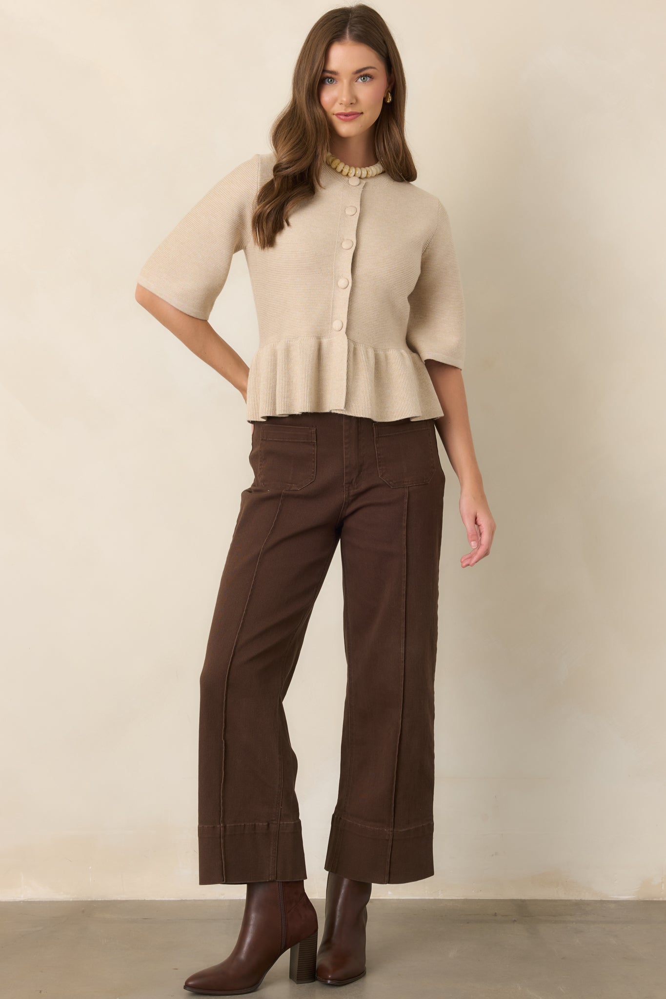 Oatmeal peplum top showcasing a structured viscose-blend knit, softly gathered waist, fitted bodice, and elegant elbow-length sleeves.