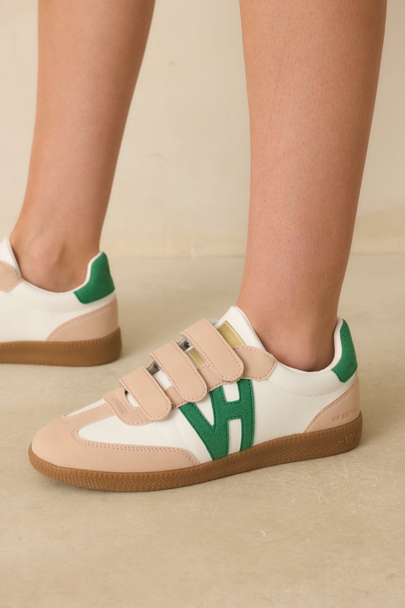 Close-up detail photo capturing the smooth ivory faux leather, gold tongue logo, and stitching.