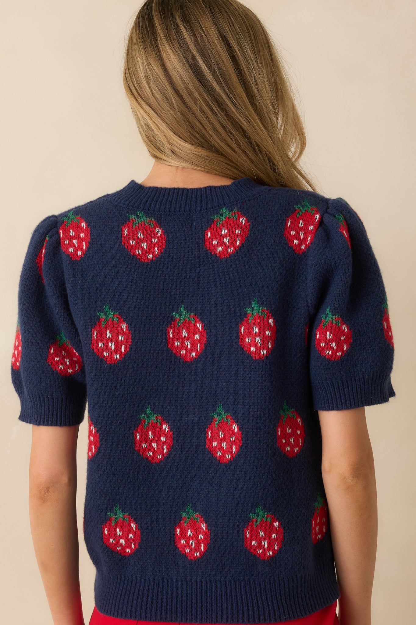 Rear view of navy knit sweater with short sleeves, relaxed fit, and allover strawberry pattern.