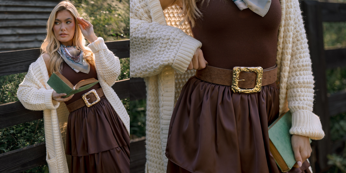 Split image of a woman in a brown ruffled midi dress, an ivory cardigan, a chunky brown and gold belt, and a blue multi print scarf. In the first image she is leaning against a fence in front of a barn while reading a book. In the second, we see a close up of the belt sitting on her waist over the dress. 