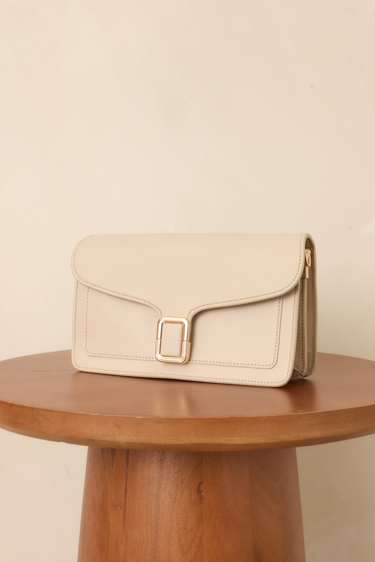Rectangular off-white handbag with smooth faux leather, contoured flap, polished gold-tone hardware, and detachable strap.