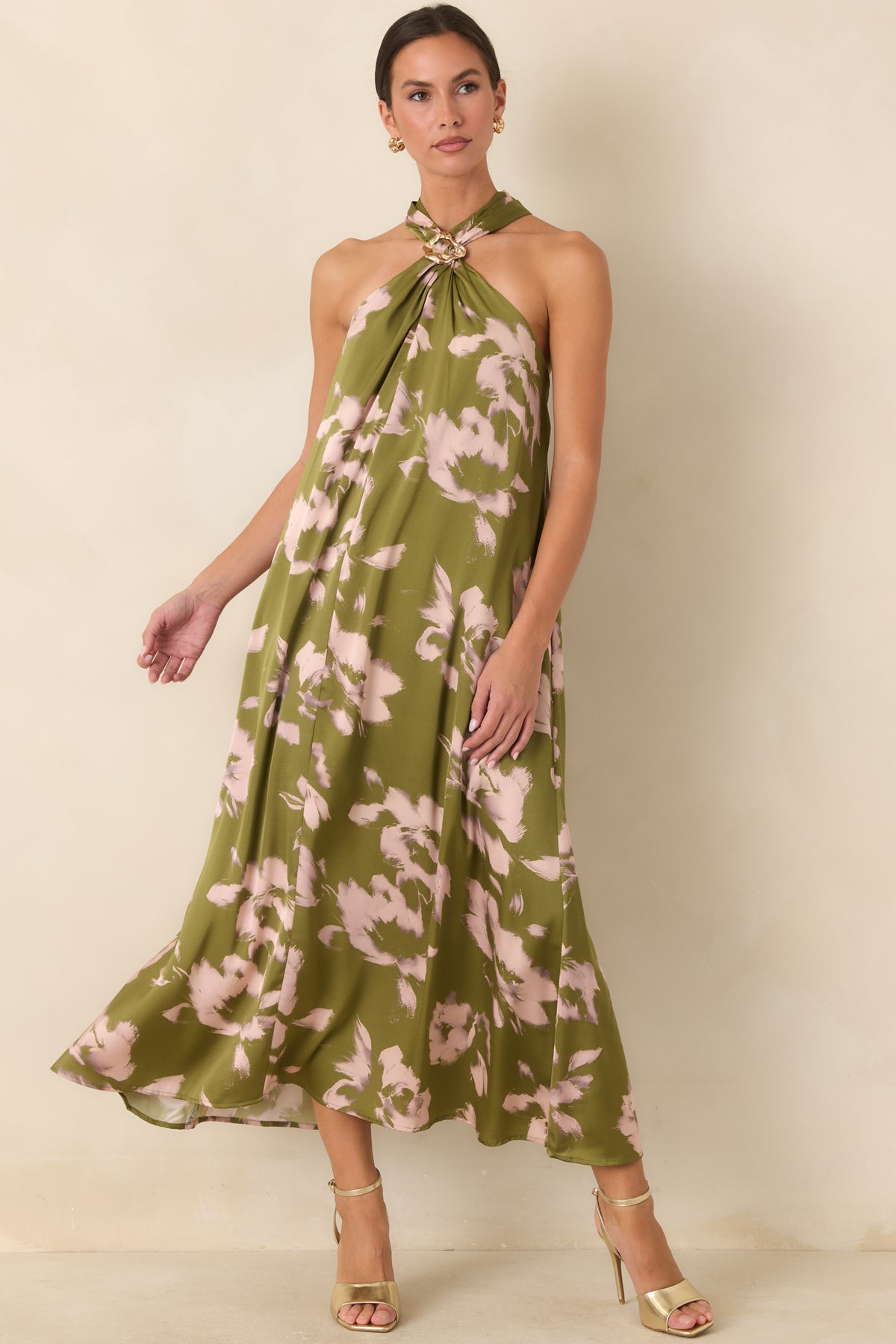Olive maxi dress accented by blush blooms and a gathered gold-tone halter neckline with flowing folds.

