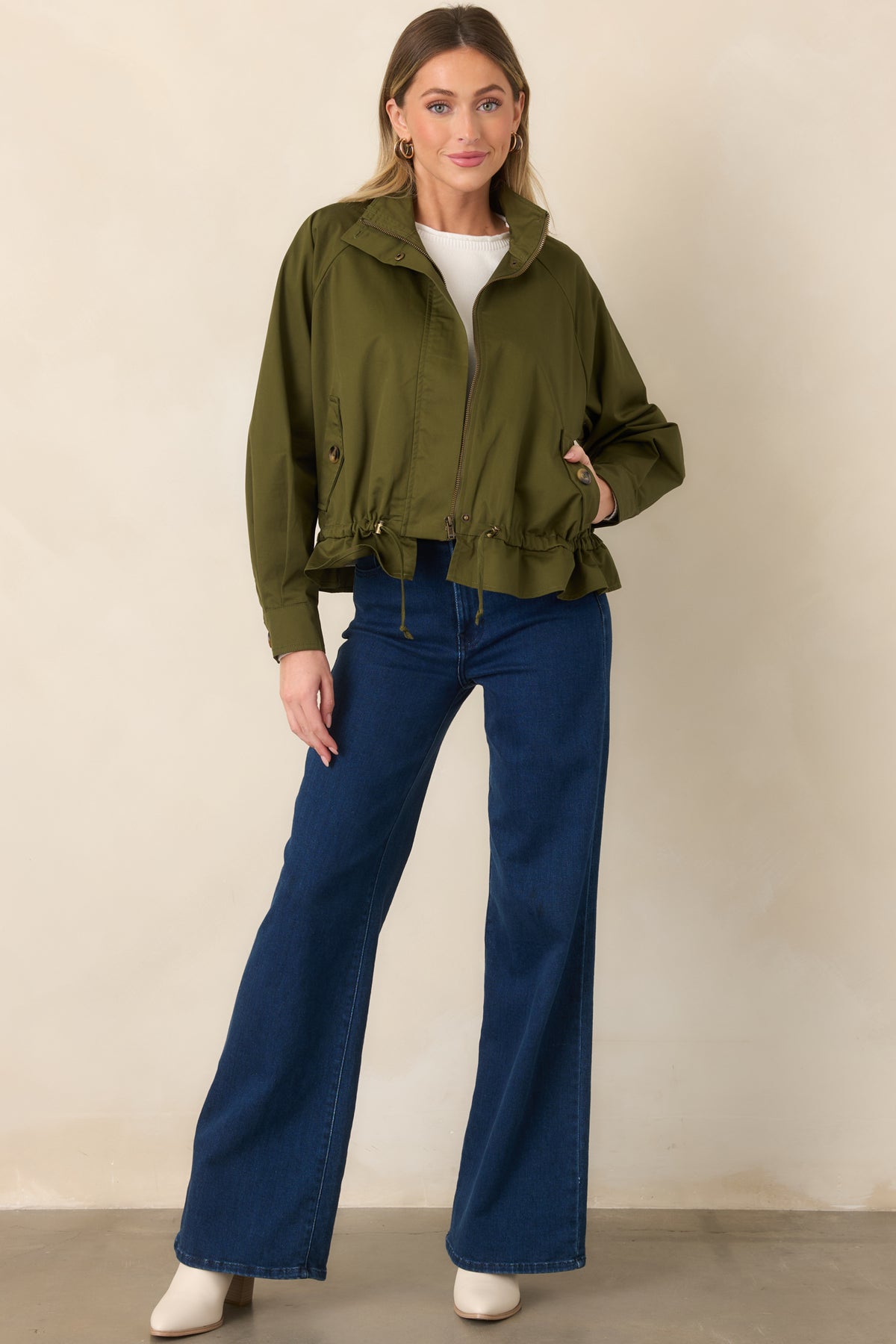 Cotton olive jacket with a clean stand collar, adjustable waist, and softly flared ruffled hem.