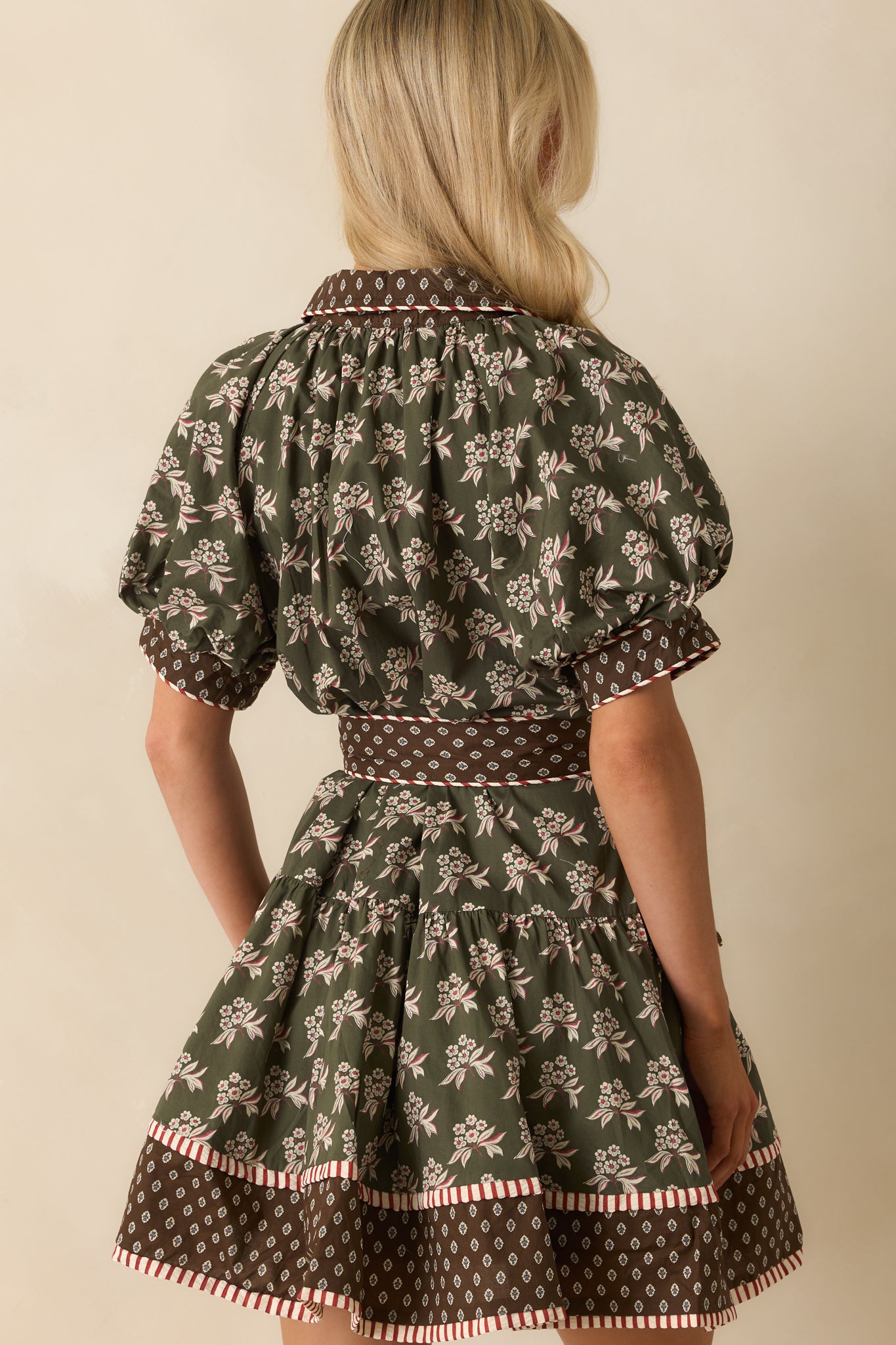 Rear view of olive green floral mini dress with puff sleeves, tiered skirt, and optional belt.