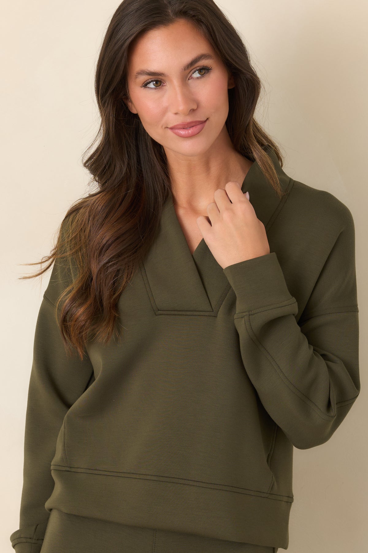 Olive-green long-sleeve top featuring banded cuffs and subtle seams along the relaxed silhouette.