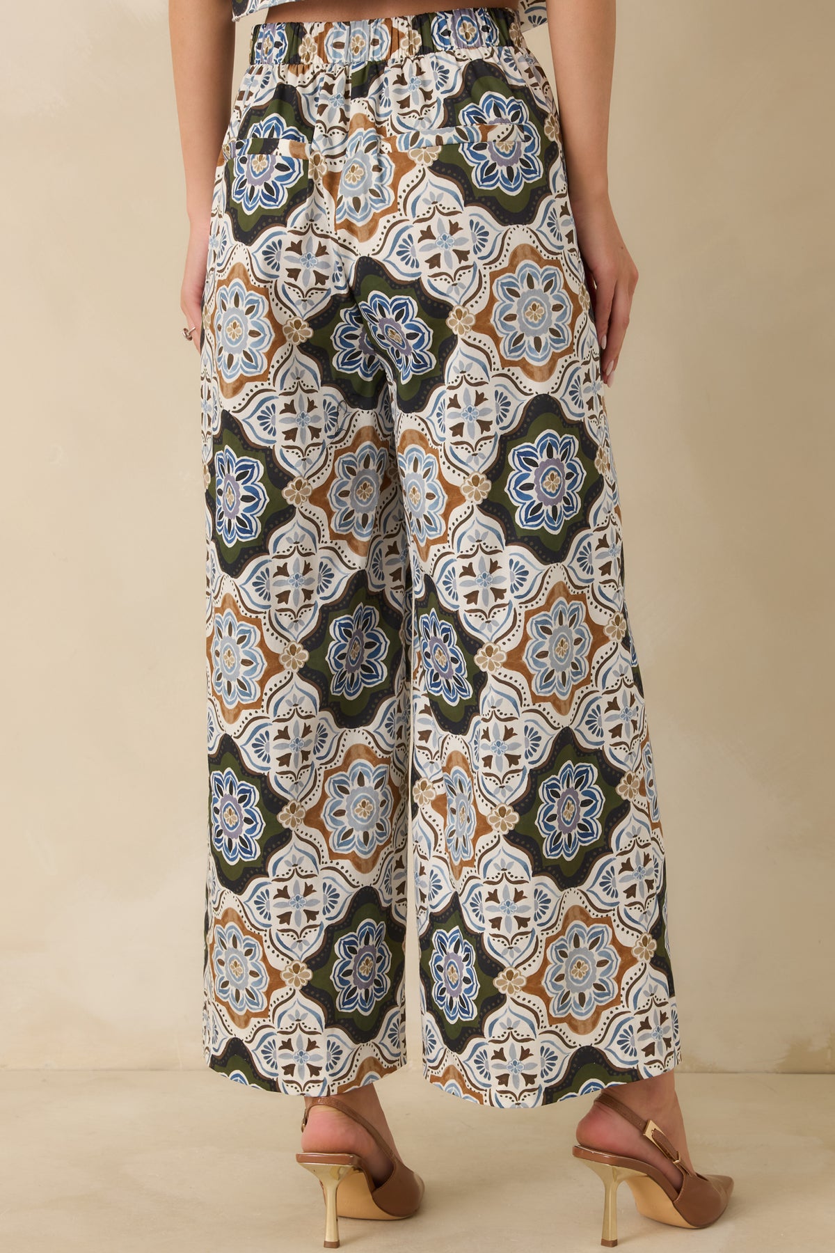 Rear view of the olive green medallion pants showing the elasticized waistband and faux welt pockets.