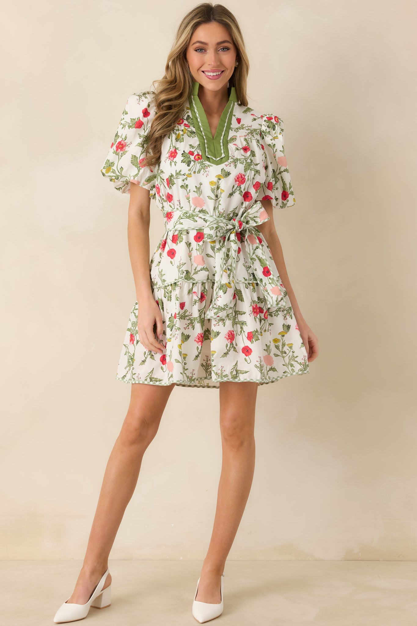 Front-facing full body view of the olive green mini dress featuring puff short sleeves and a V-neckline with contrast trim.