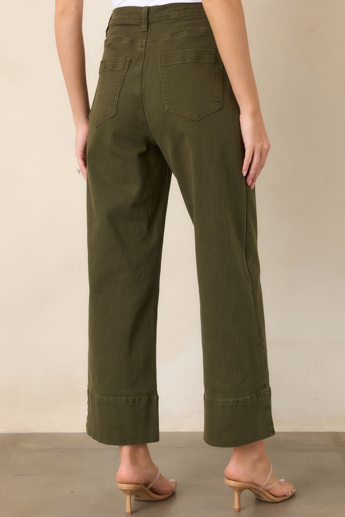Rear view of the olive green pants showcasing classic back patch pockets, belt loops, cropped wide legs, and cuffed hems.