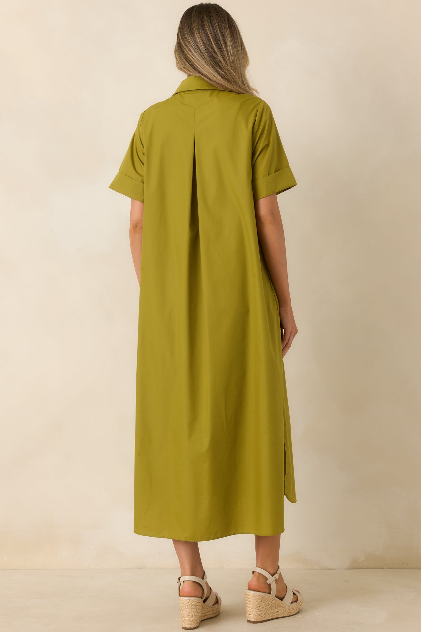 Back view of the olive green woven maxi dress featuring a relaxed A-line silhouette, short sleeves, and smooth draped finish.