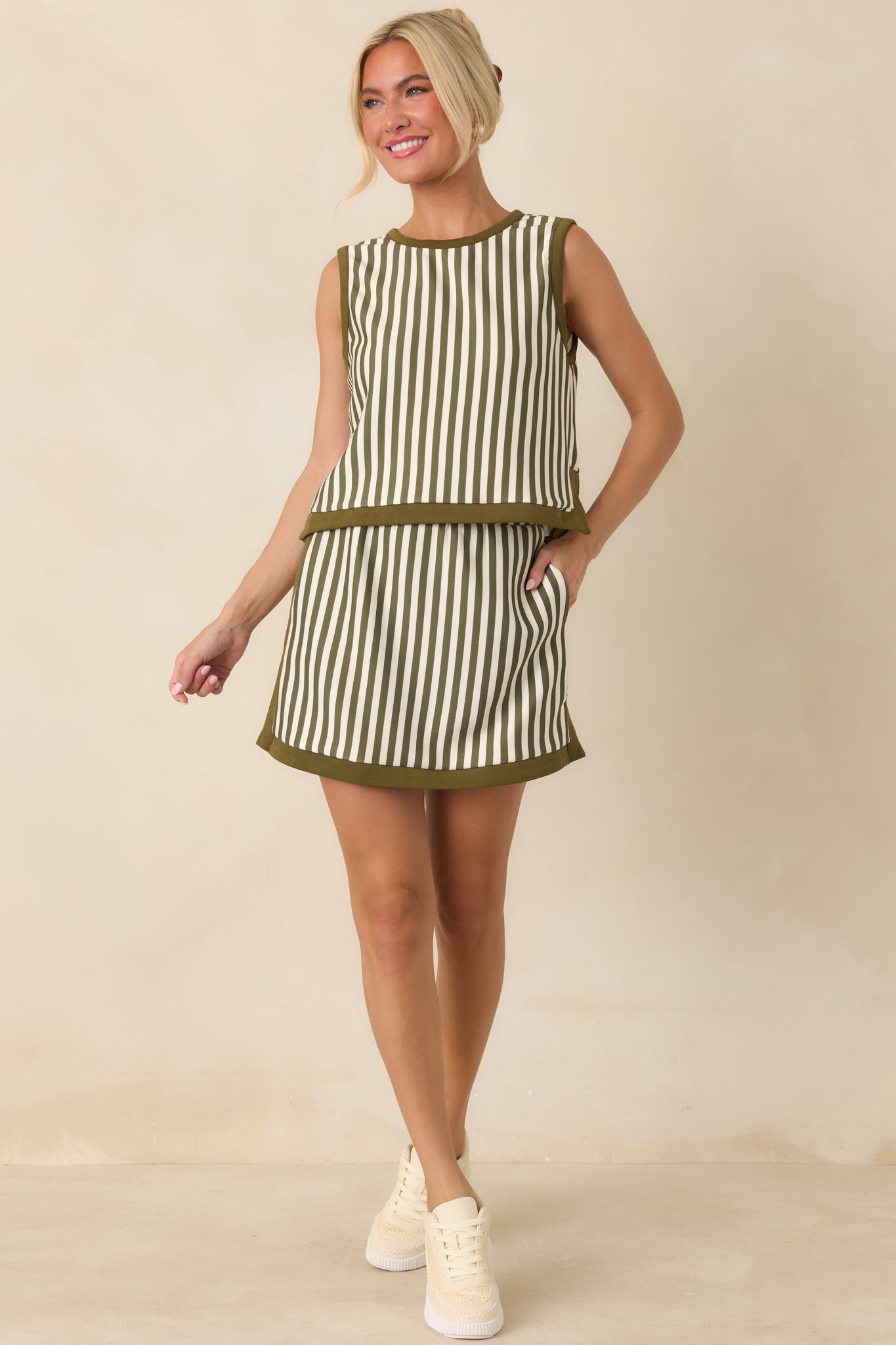 Olive and ivory vertically striped mini skirt with a high-rise waistband, side pockets, contrast olive trim, and built-in shorts.
